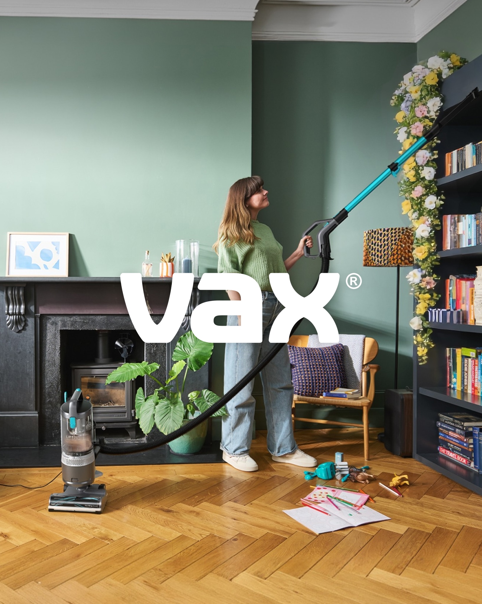 A woman using a Vax vacuum cleaner in a living room