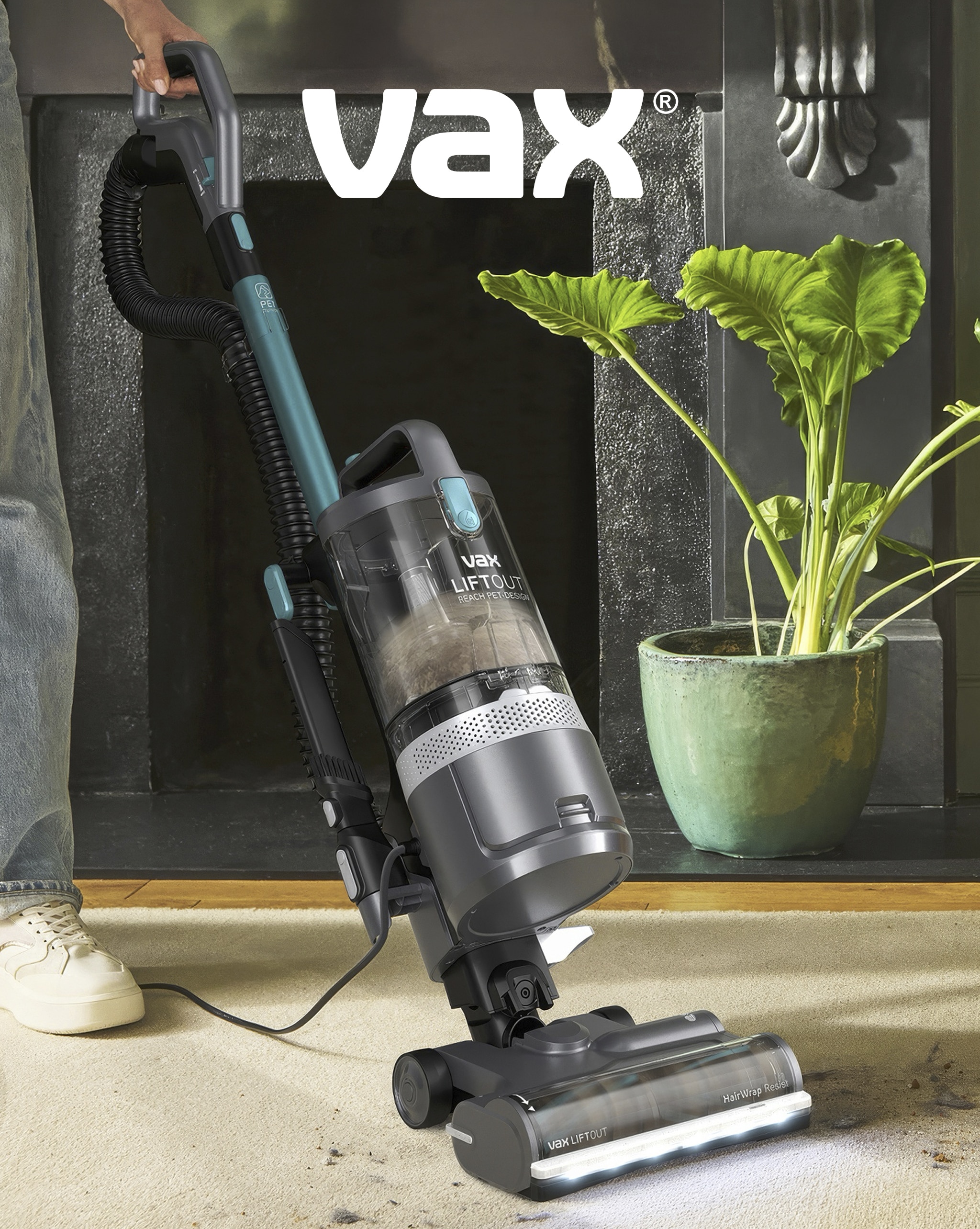 A person using  a Vax vacuum cleaner on carpet.