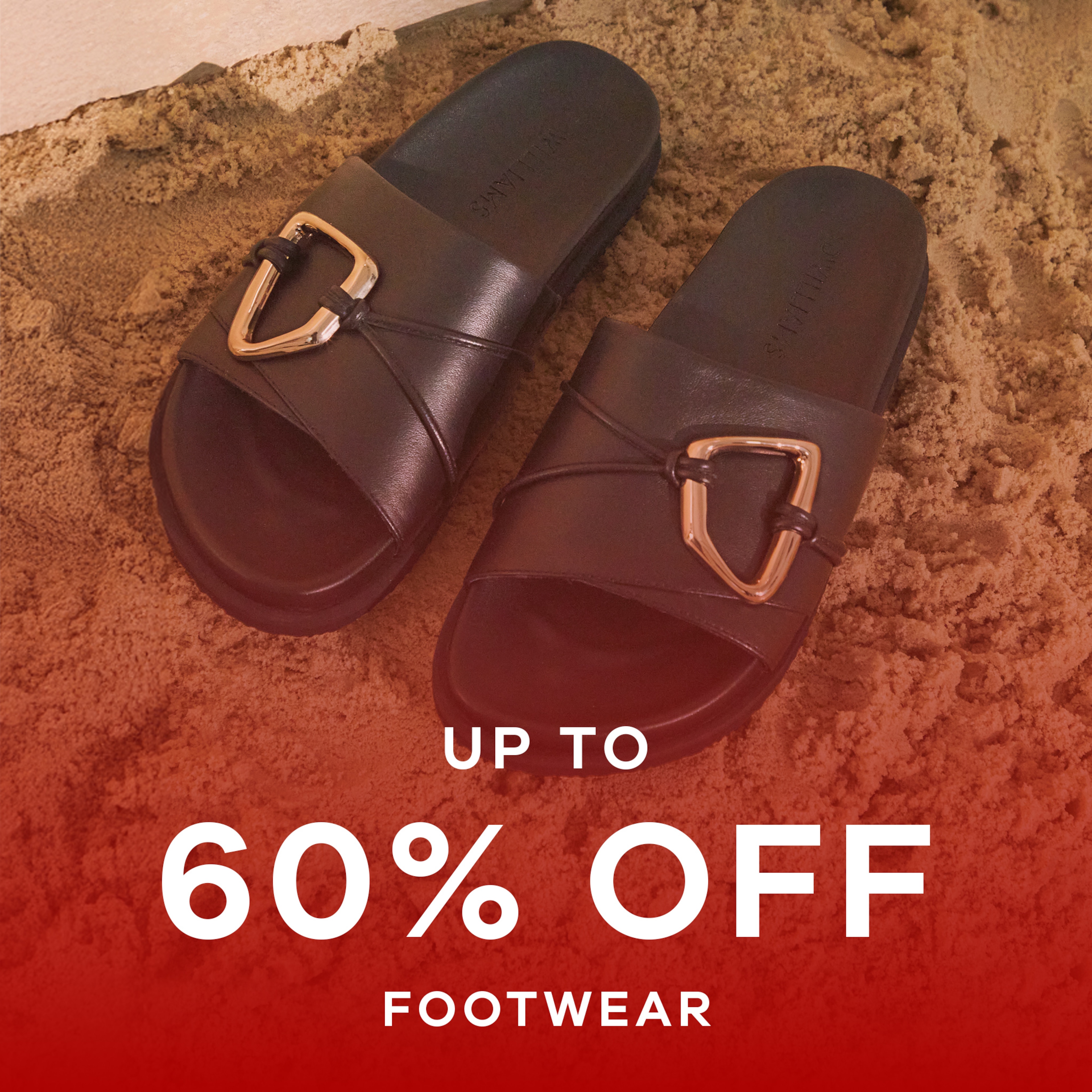 A pair of black sandals on some sand. Up to 60% off footwear.