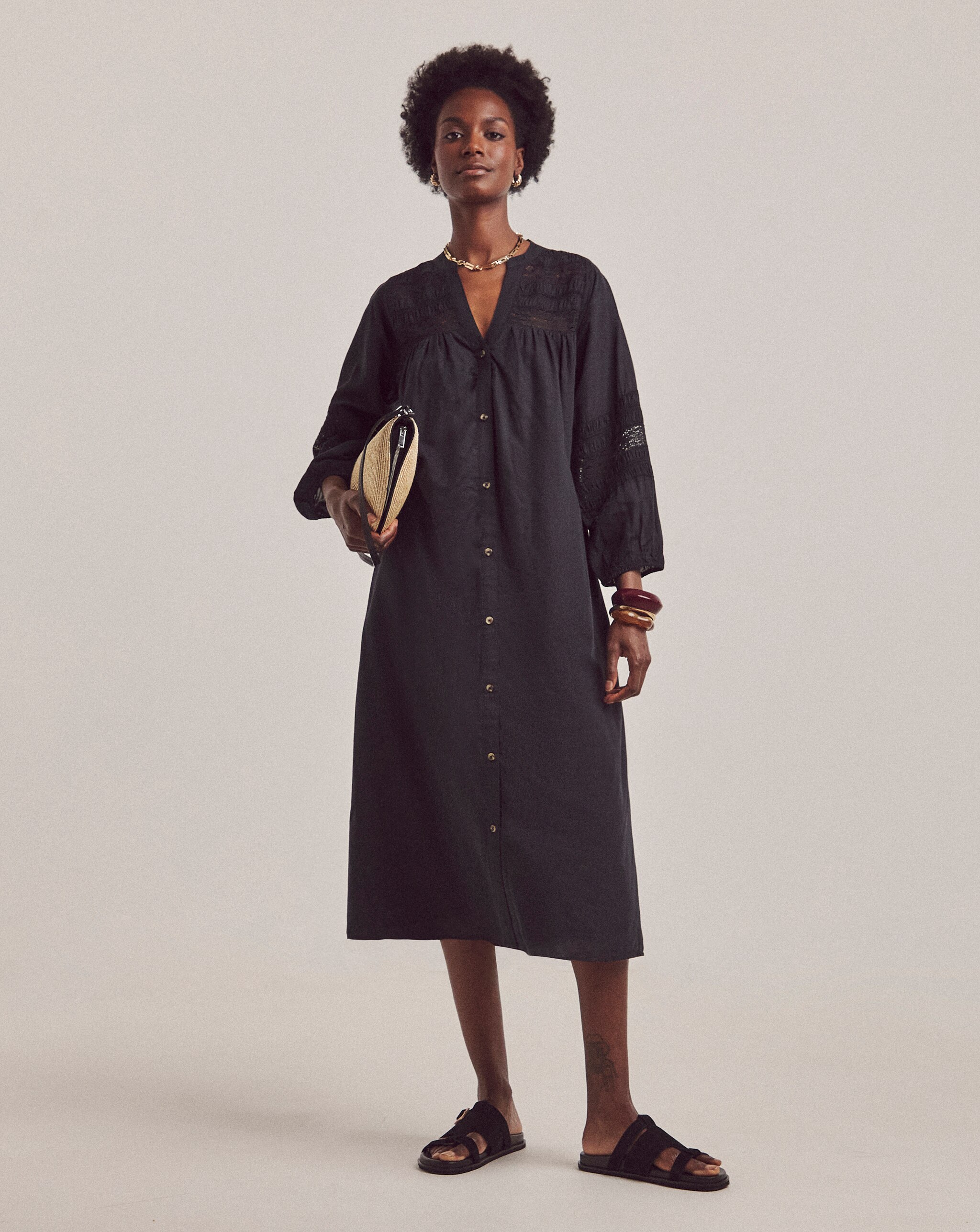 A woman wearing a black long sleeved button up dress