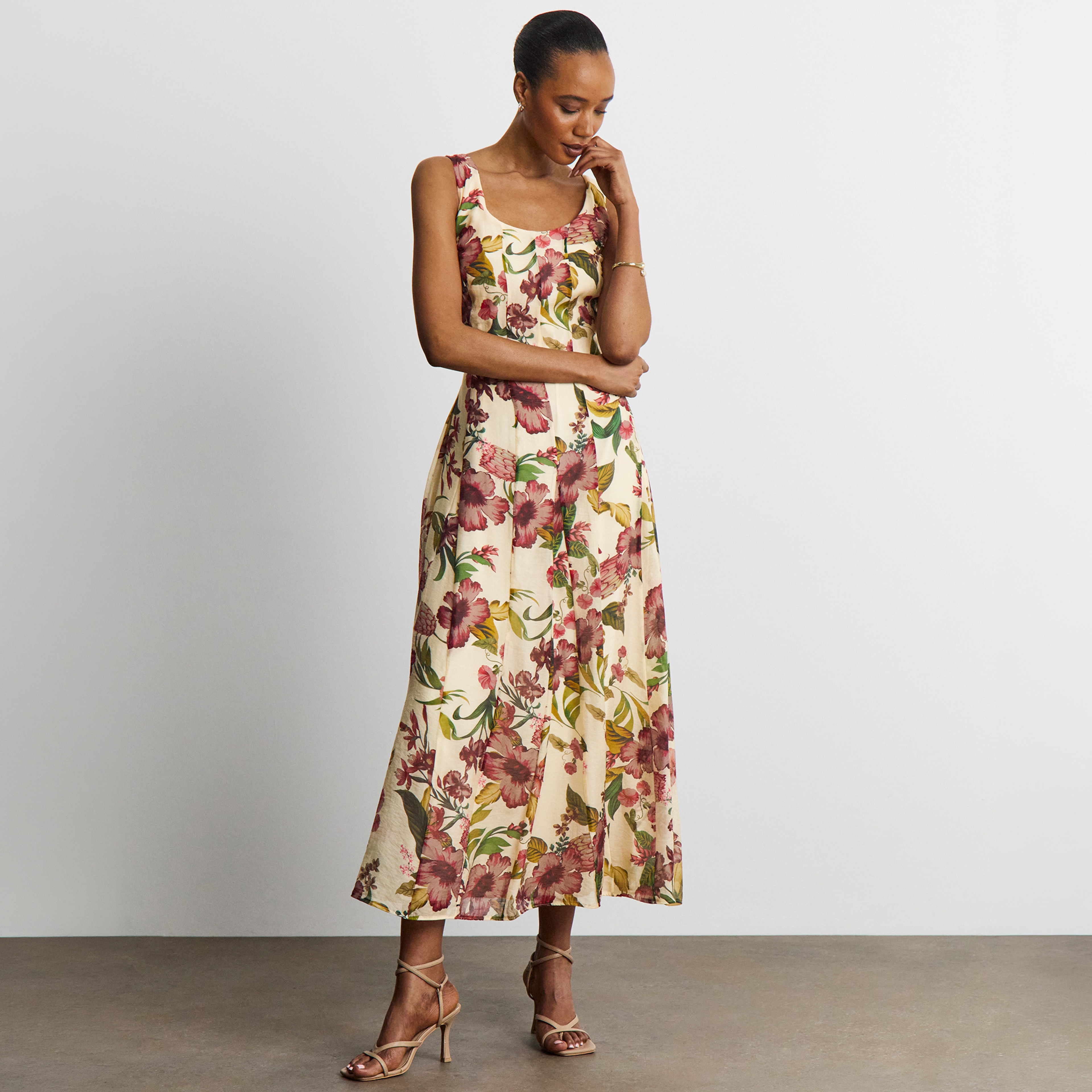 A lady wearing a cream dress with floral patterns on it.