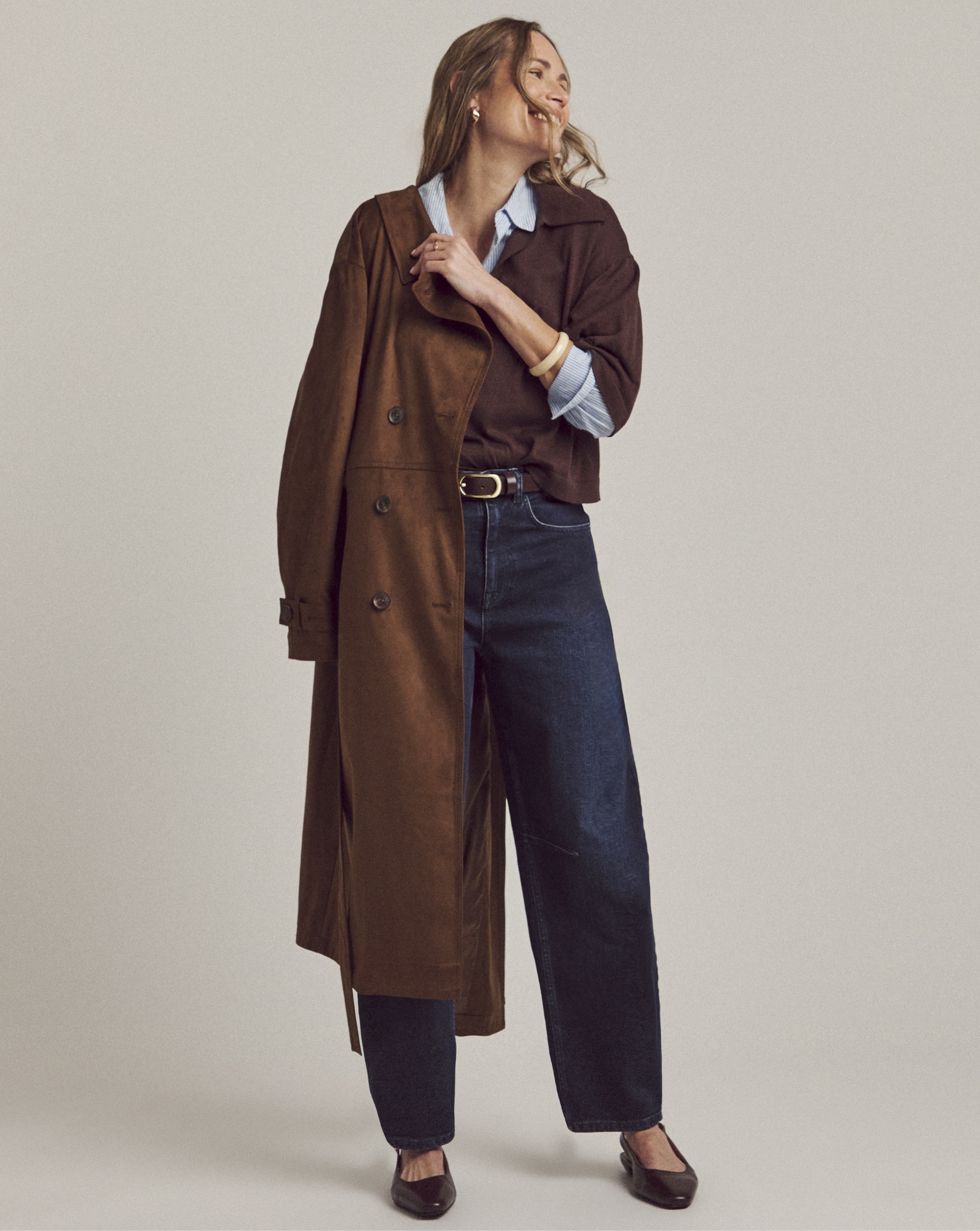 Woman wearing long brown mac and denim jeans