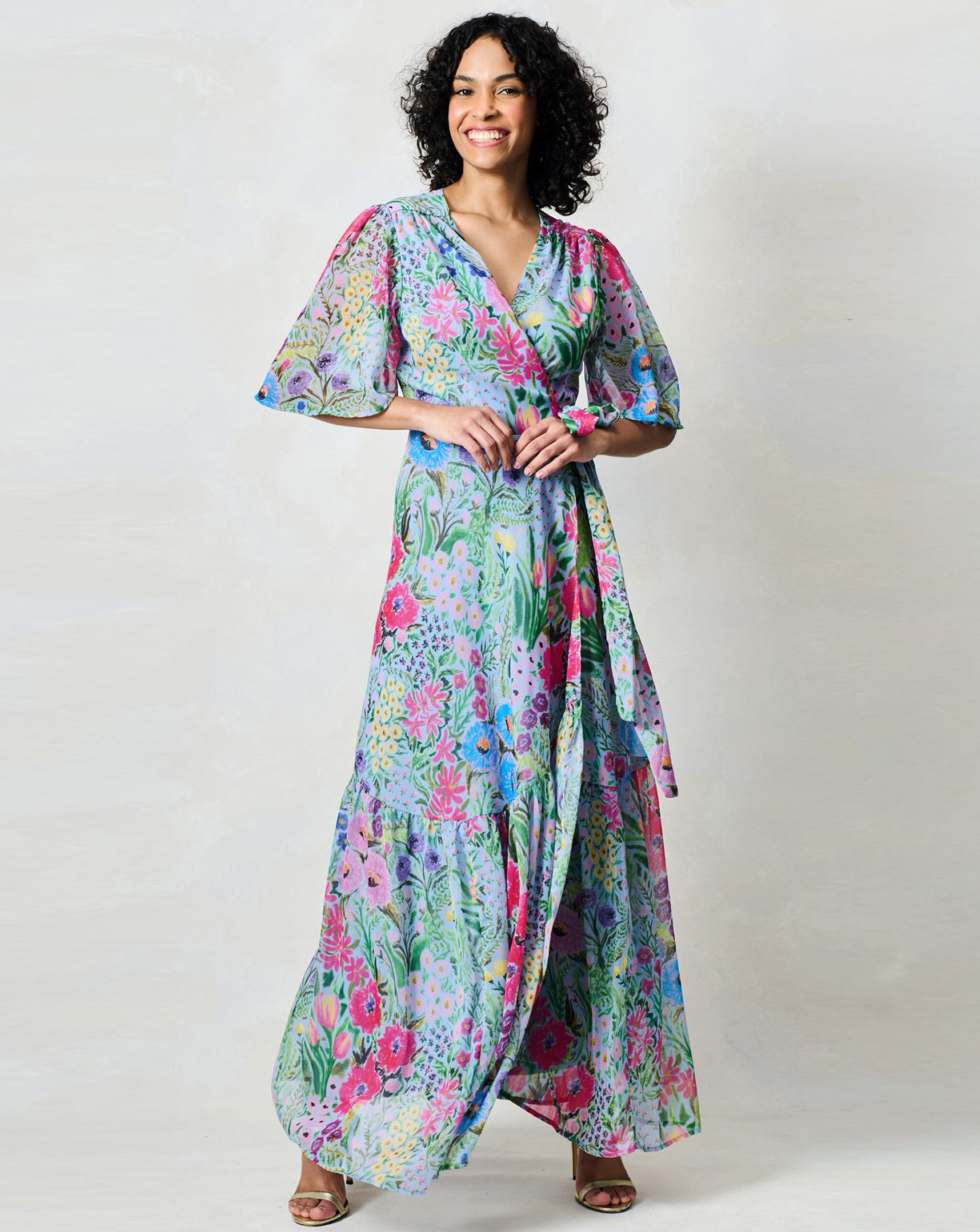 A woman wearing a blue floral waist wrap maxi dress.
