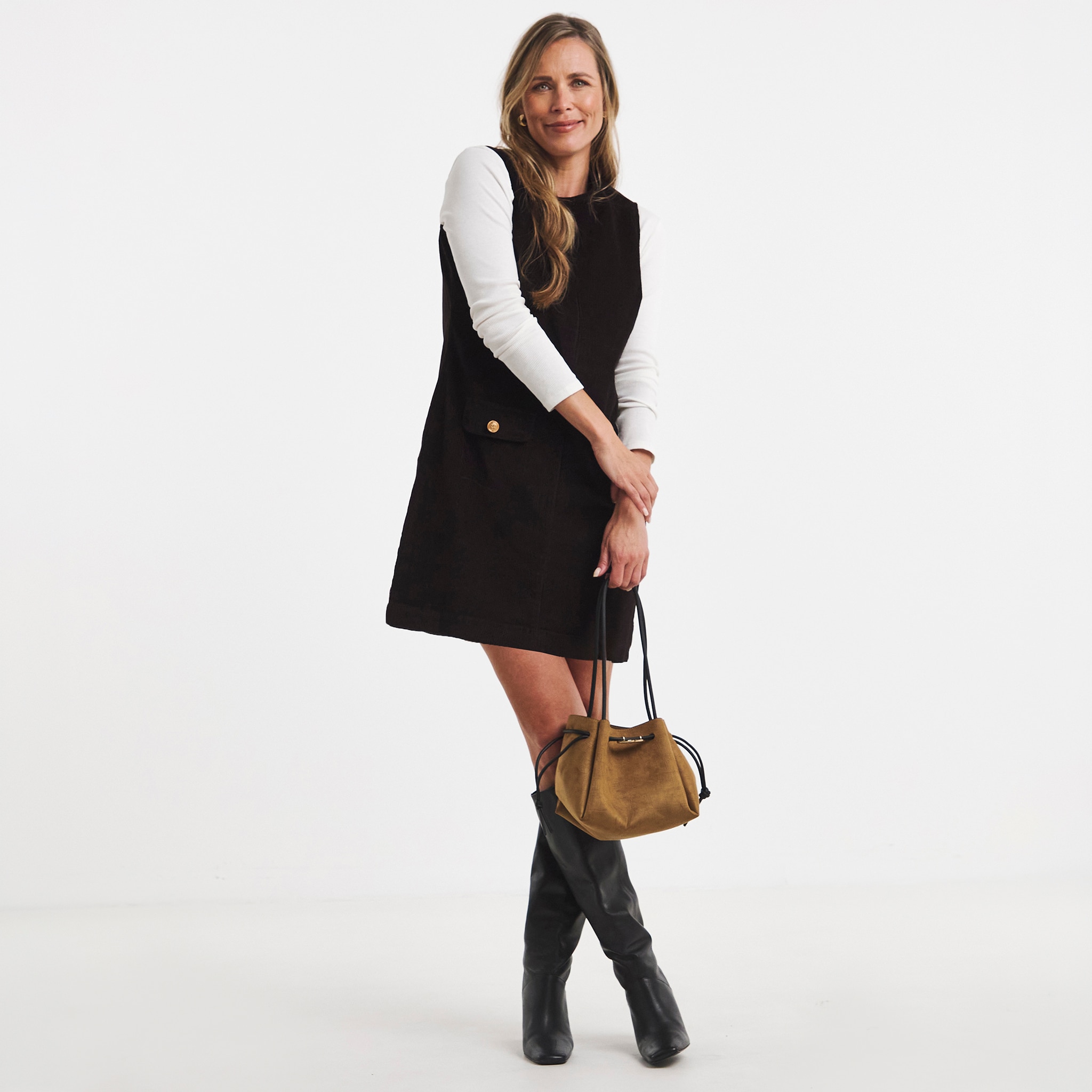 A woman stood wearing a black dress with a white long sleeved top underneath,