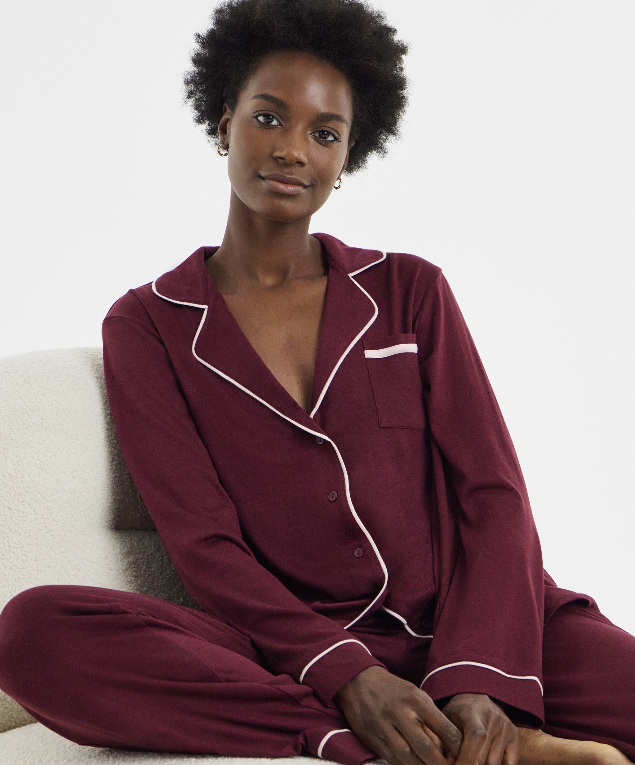 A woman sat down wearing maroon pyjamas