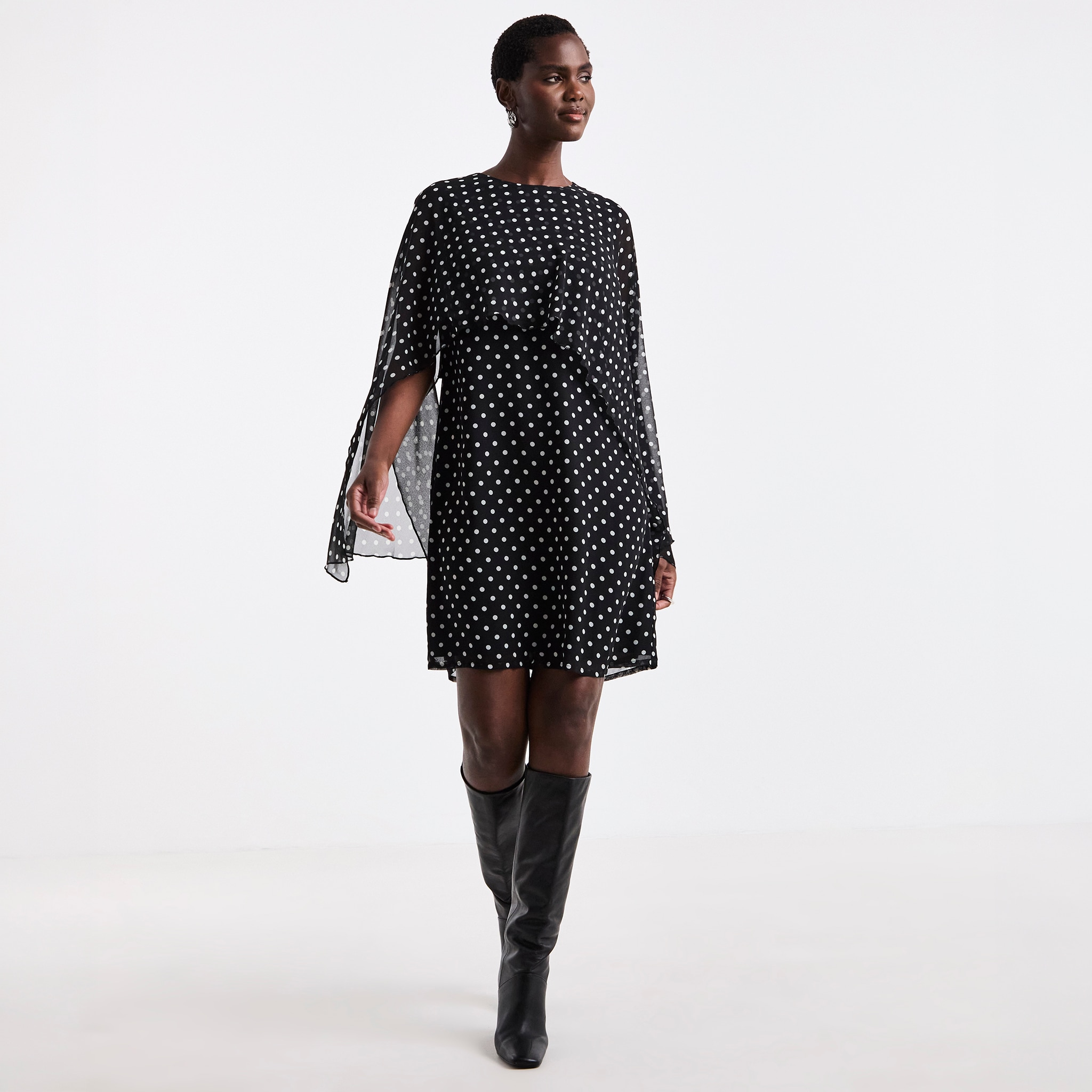A woman stood wearing a black and white polka dot short dress.