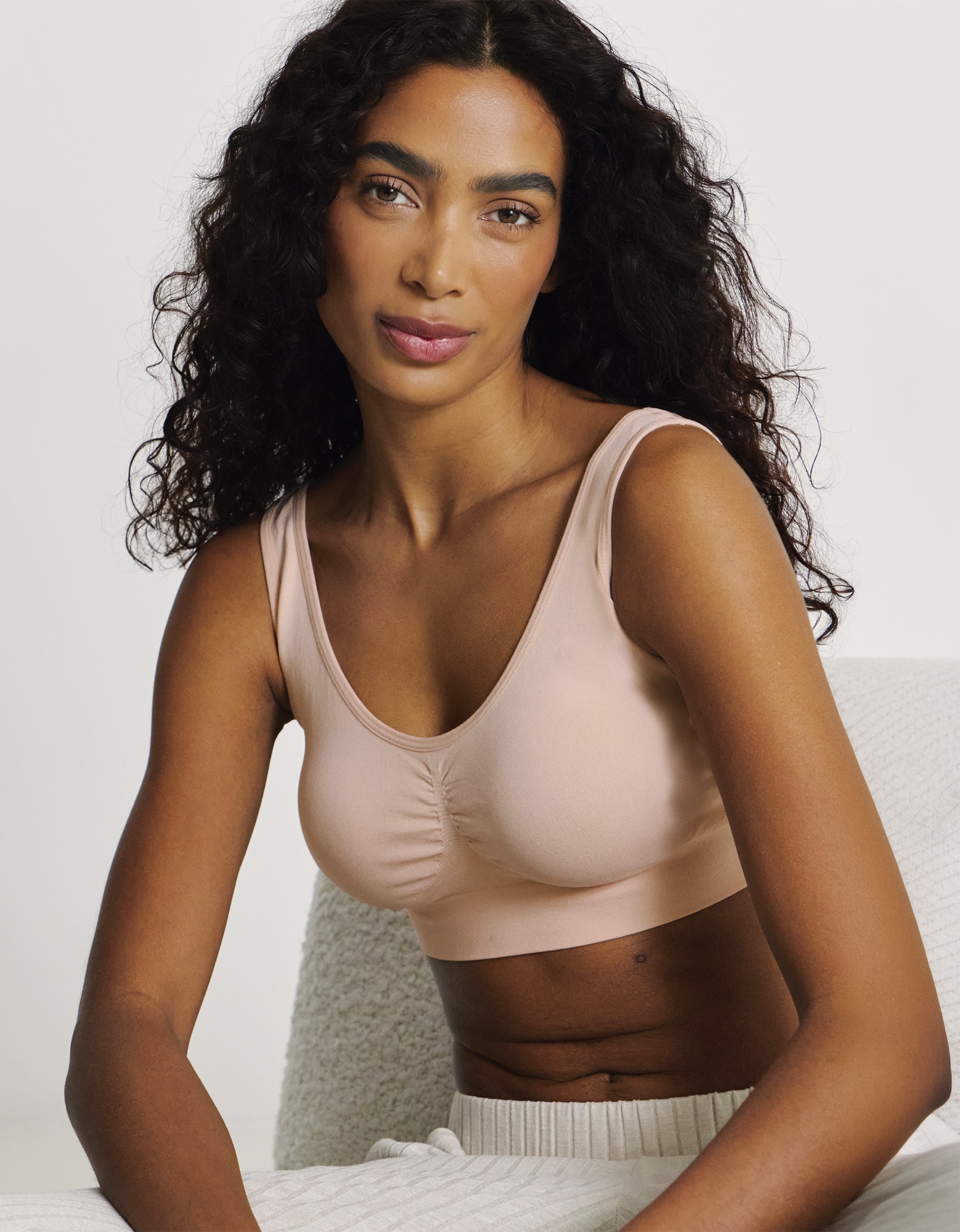 A woman wearing a blush pink comfort bra.