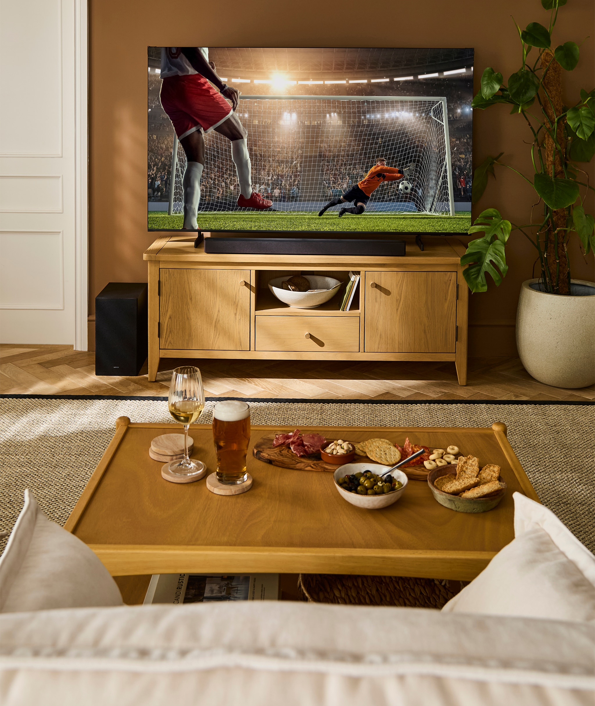 A living room with a TV on a furniture unit displaying a football match.