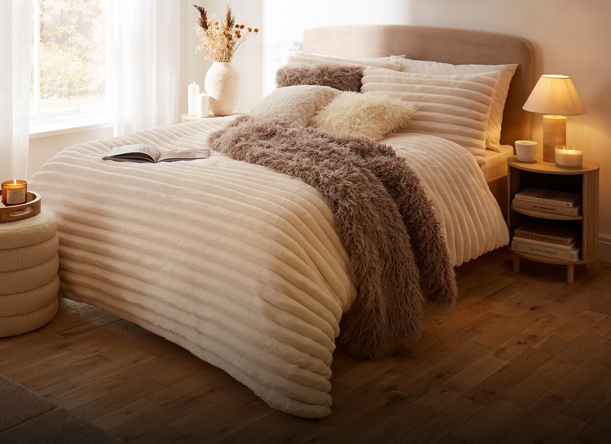A warm cosy bedroom with bedding and soft furnishings in beige and light brown.