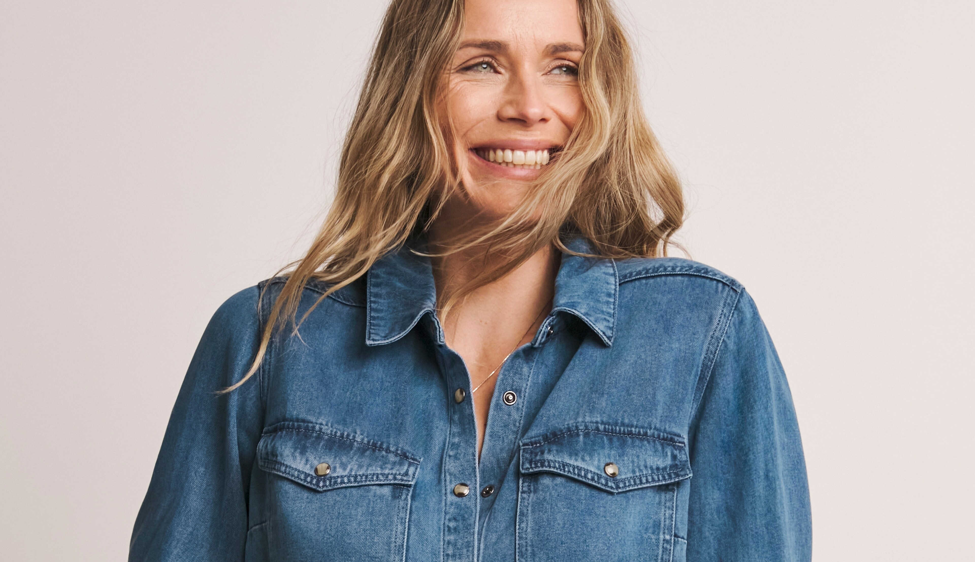 Smiling Woman in Denim Shirt Expressing Happiness and Warmth
