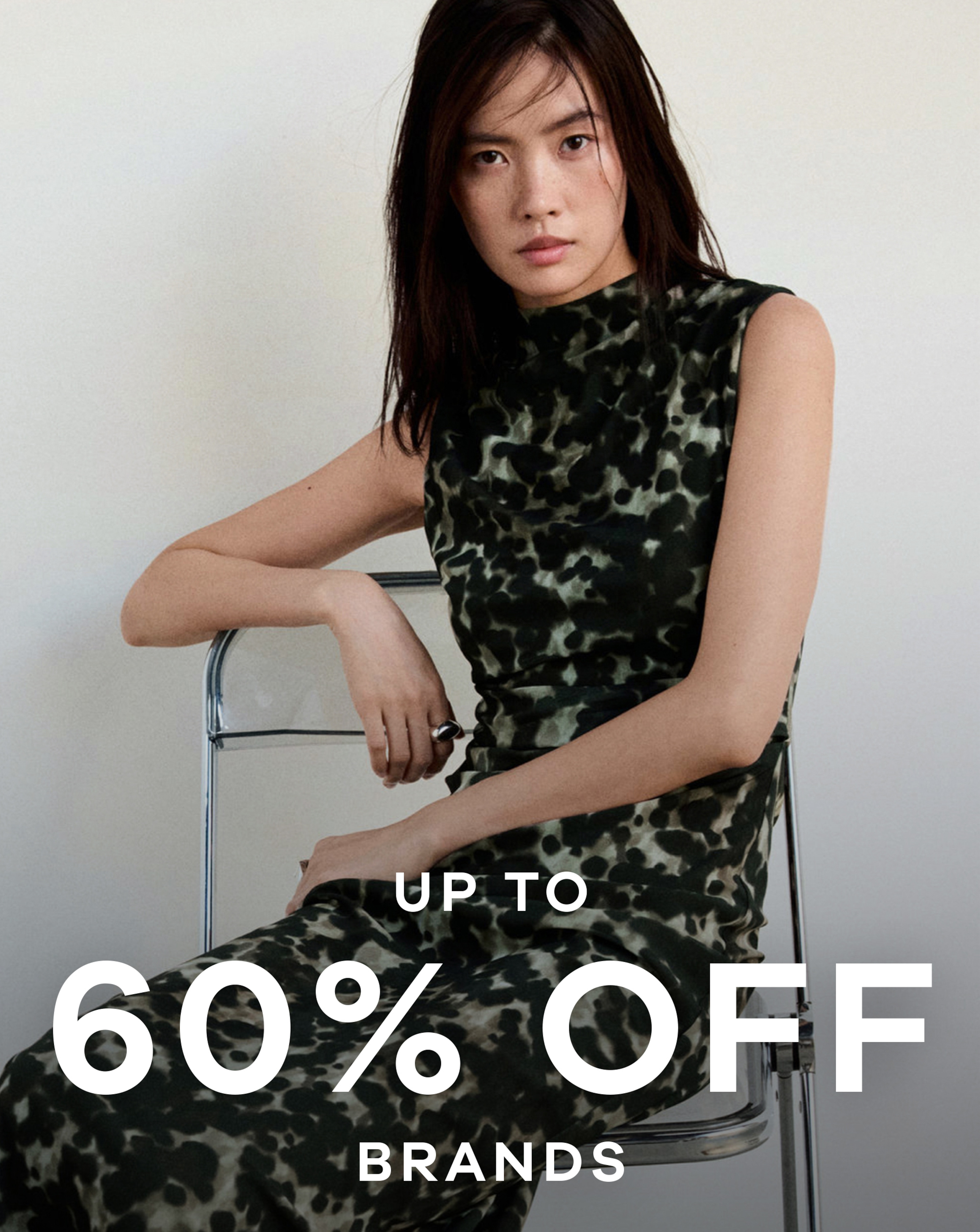 A woman sat on a chair wearing a black and green patterned dress.