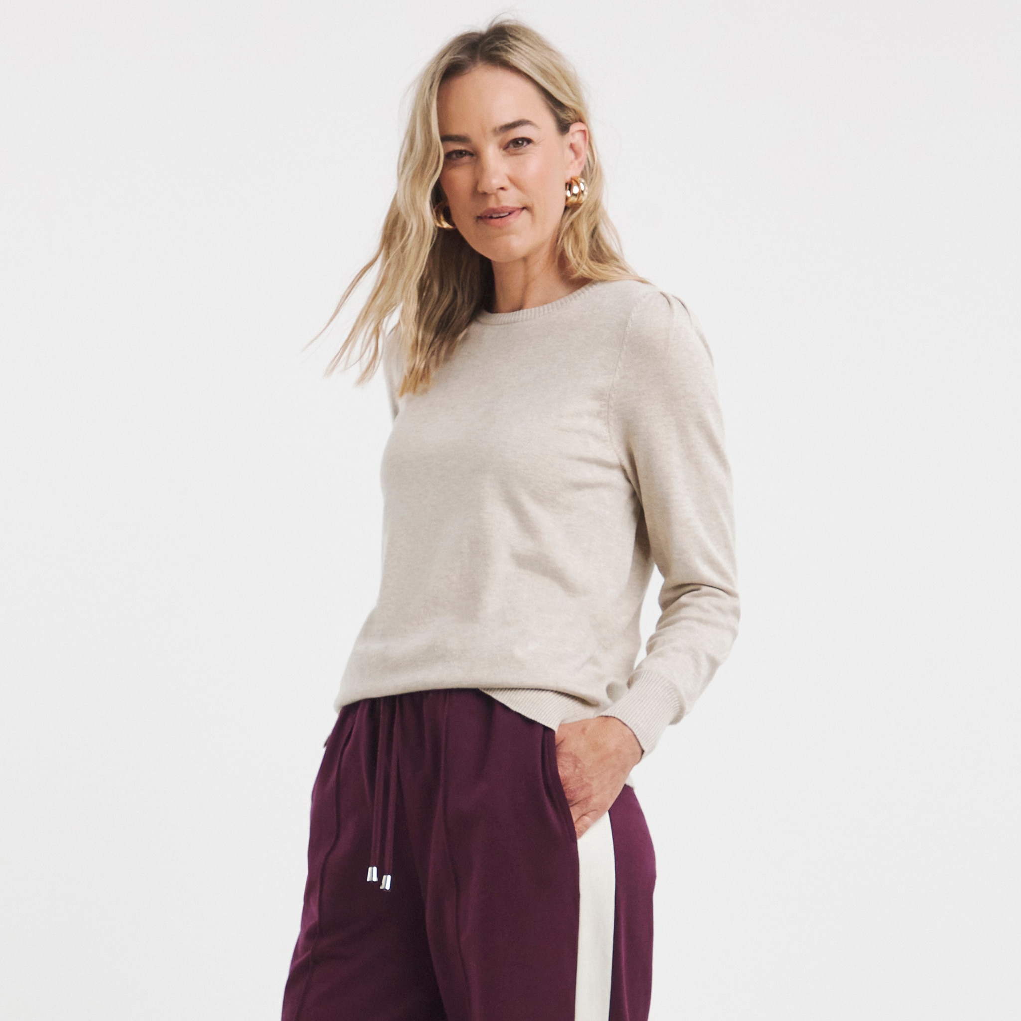 A woman wearing a beige crew neck jumper.