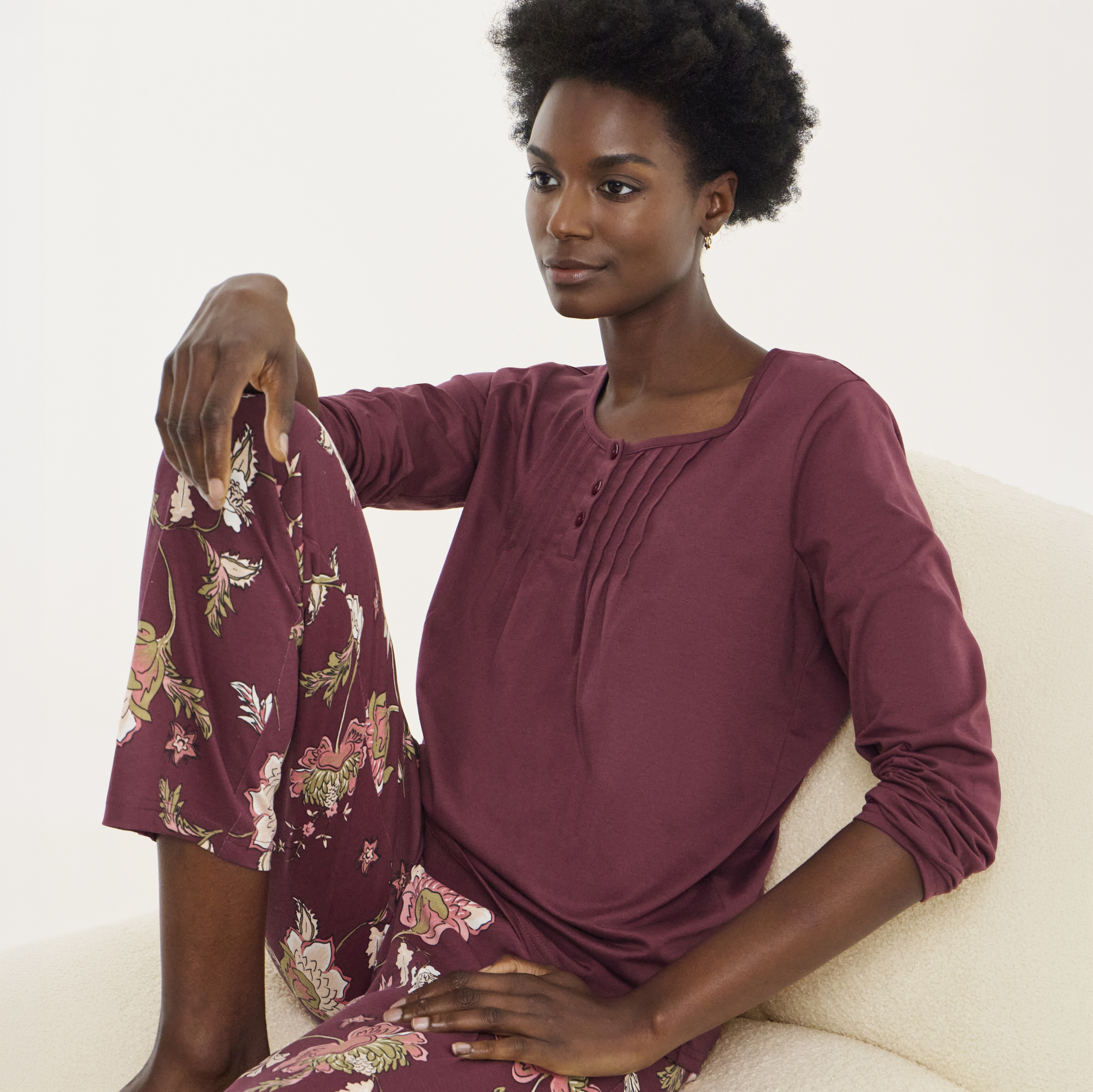 A woman sat down wearing a burgundy pyjama set.