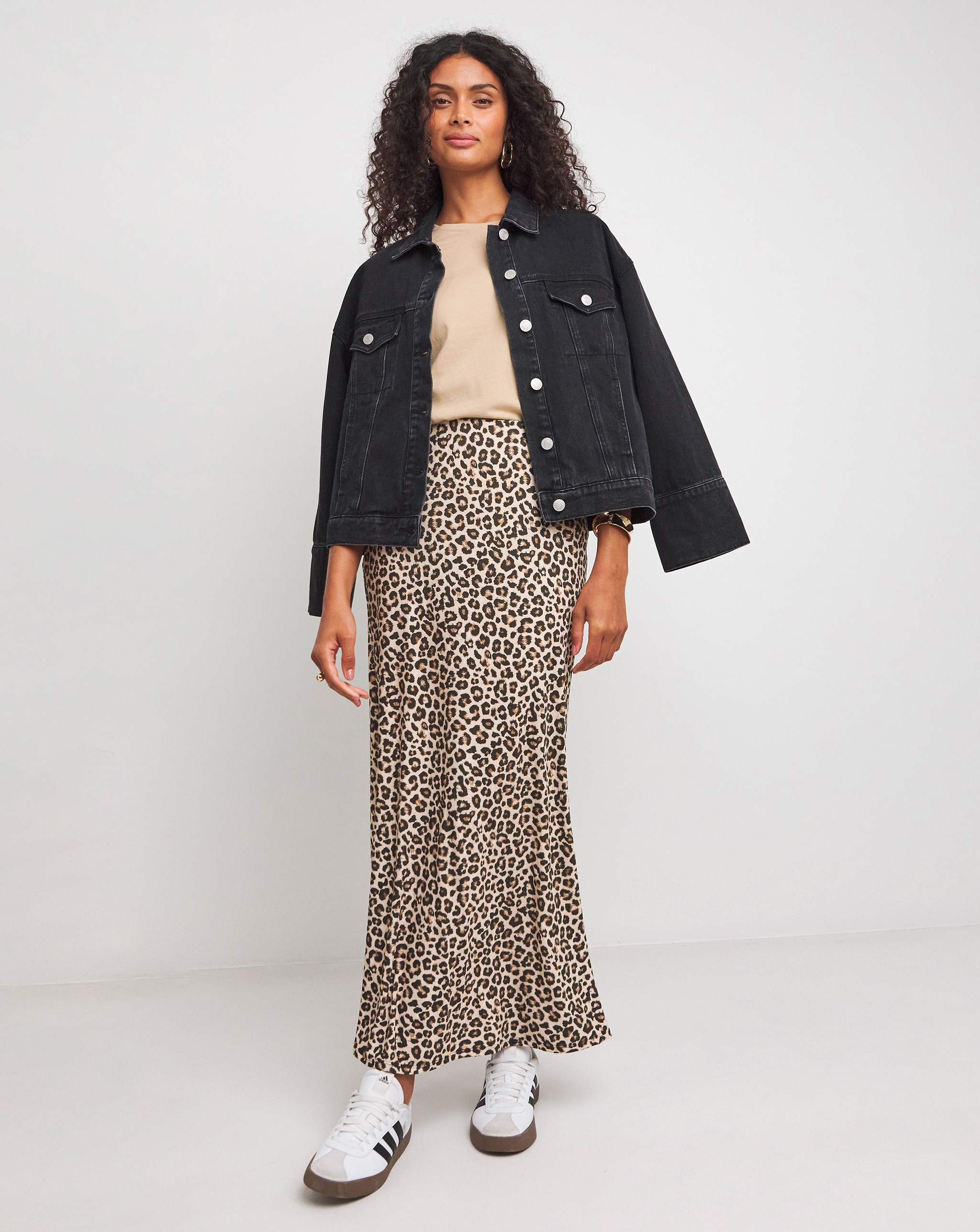 Person wearing a leopard-print skirt with a denim jacket over a cream-coloured top.