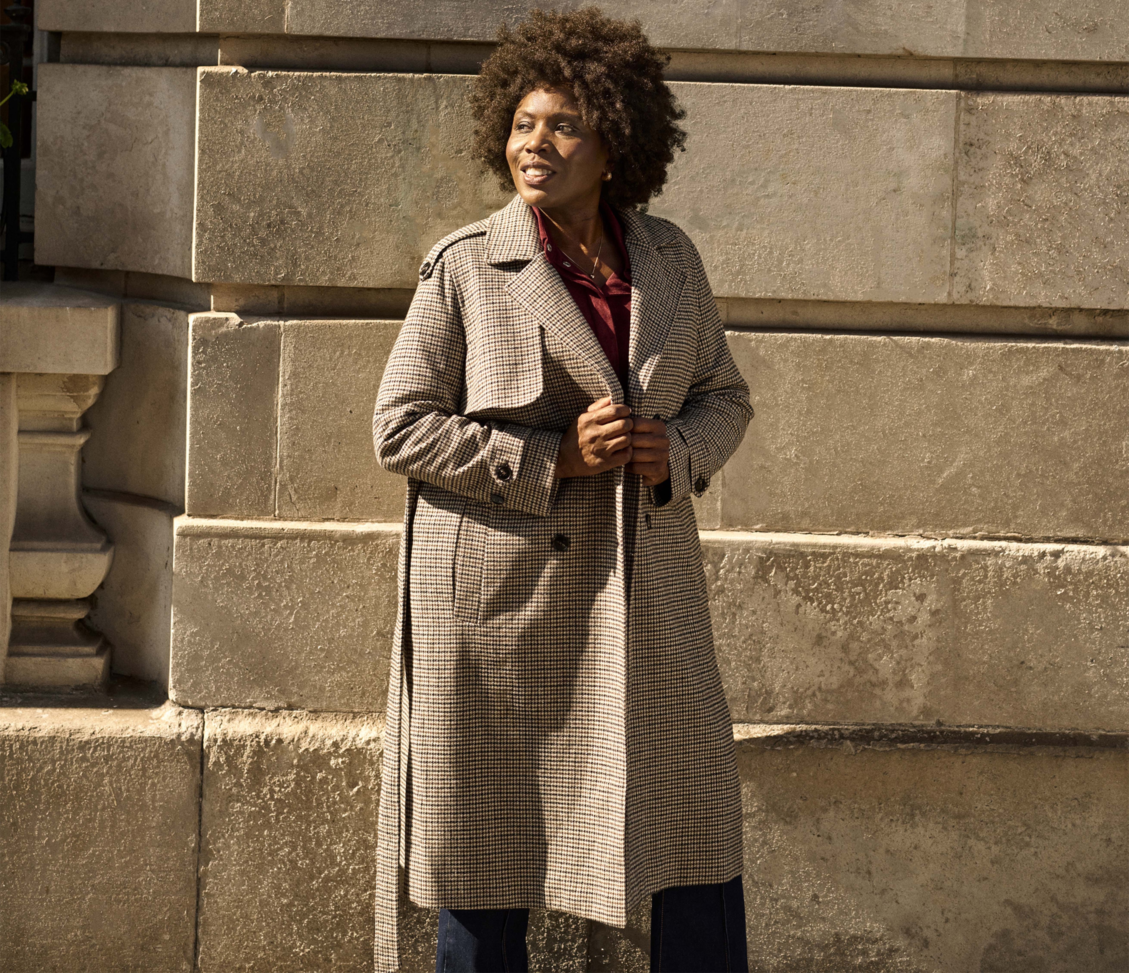 A woman stood up wearing a houndstooth check trench coat