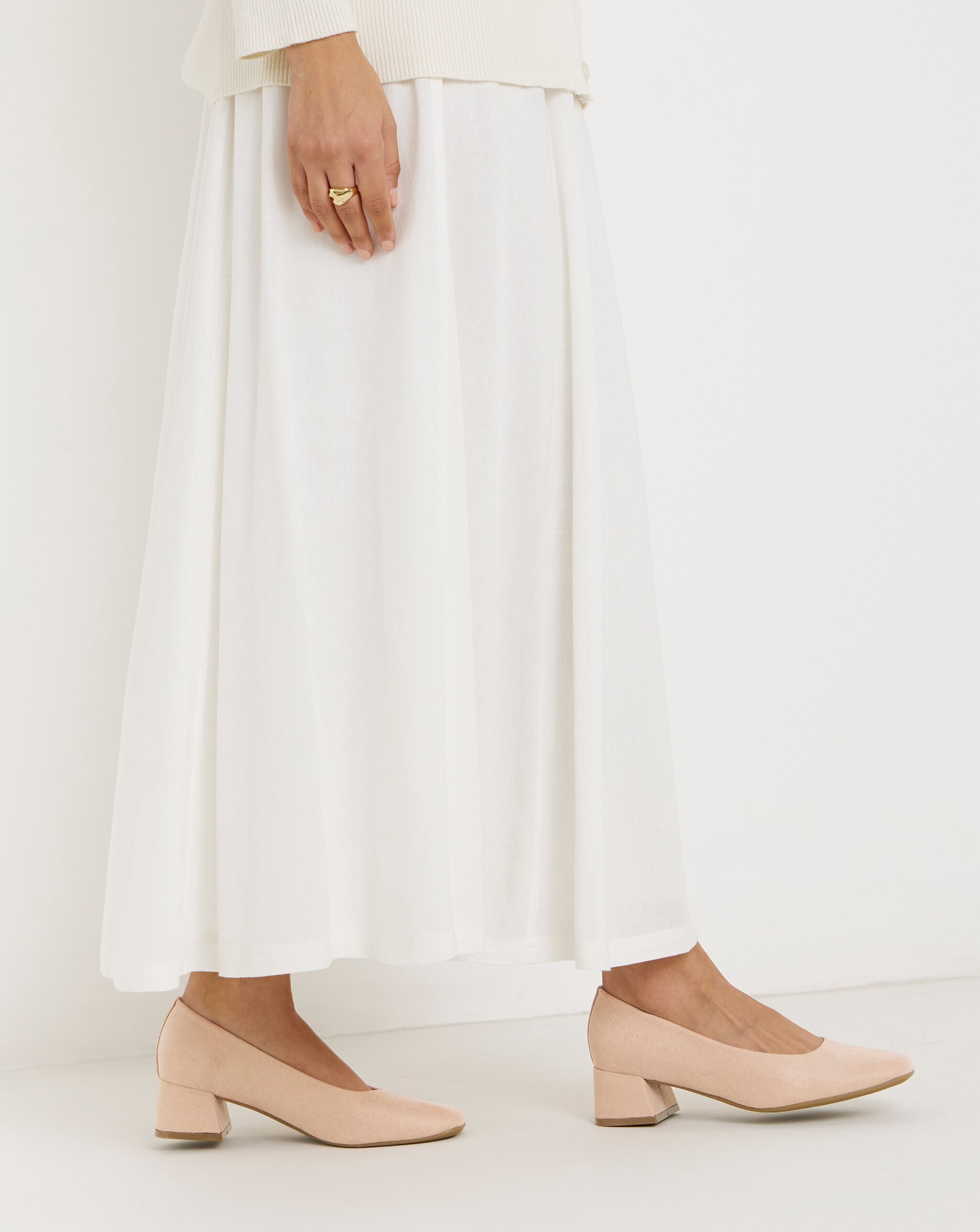 A person wearing soft pink low block heel court shoes