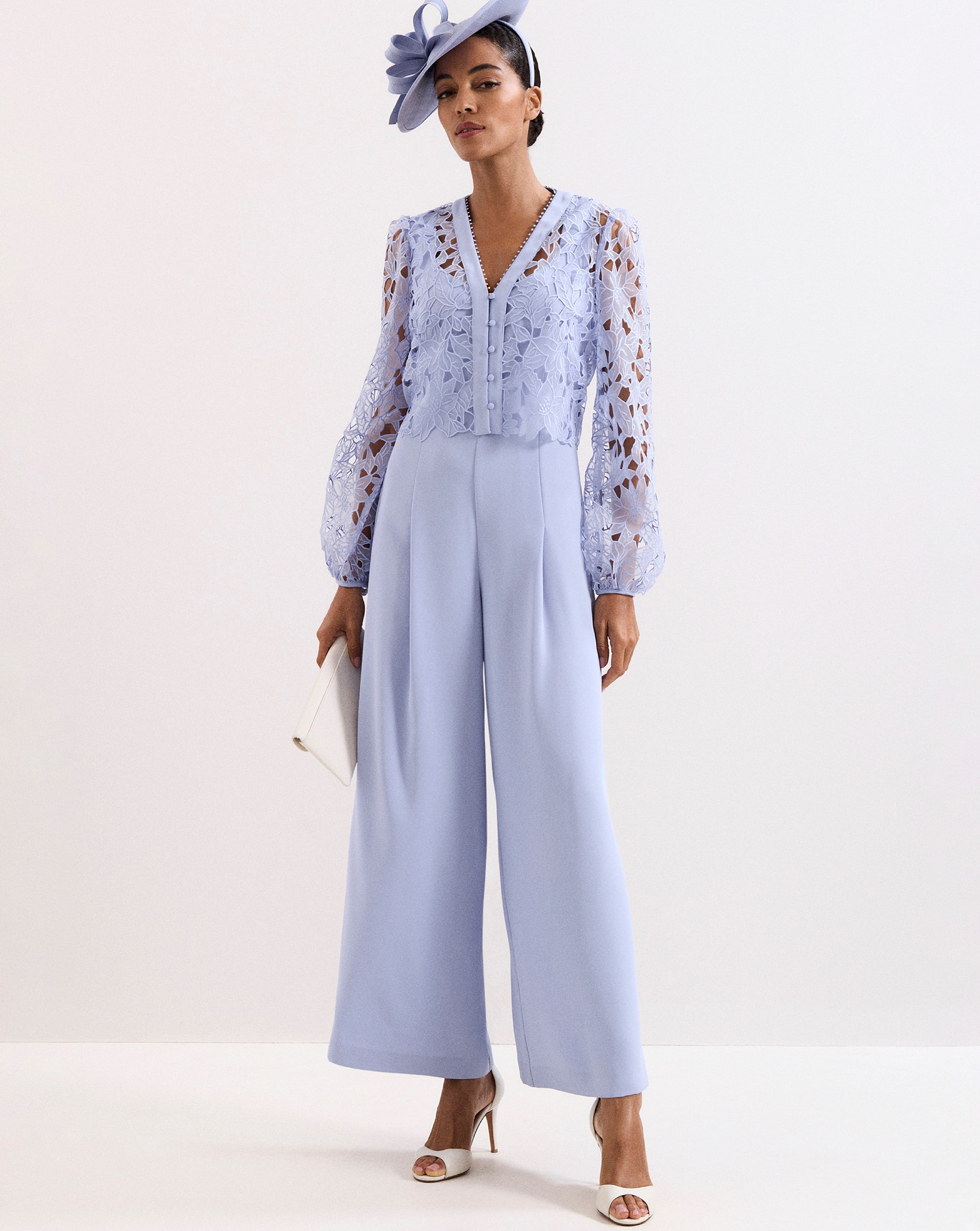A woman wearing a pale blue lace top jumpsuit