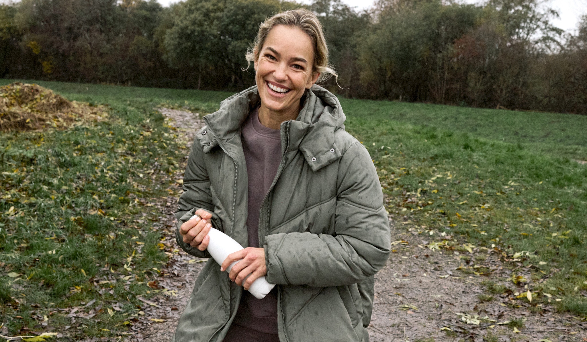 A lady outside wearing a green quilted coat.