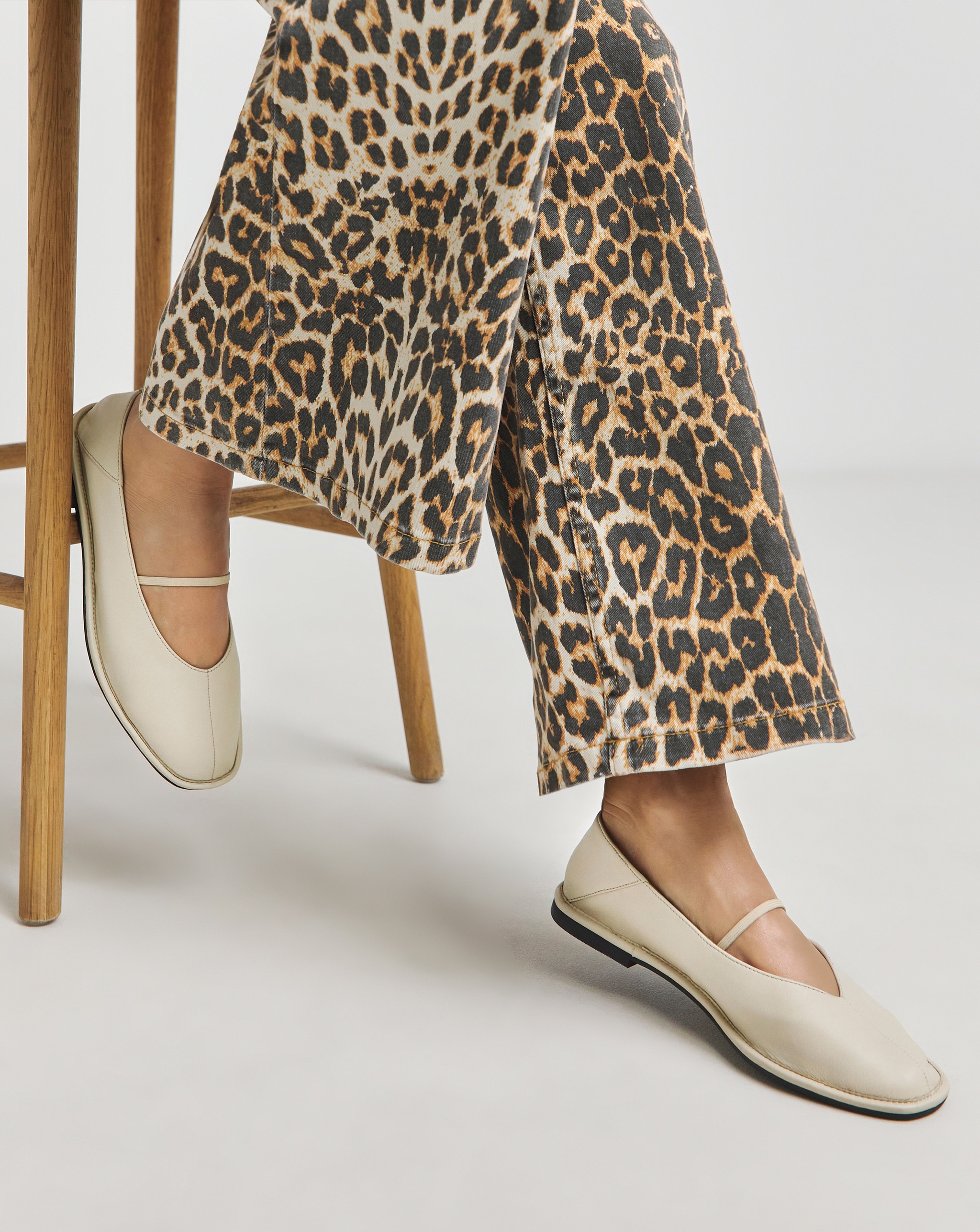 Close‑up of leopard‑print trousers and cream-coloured flat shoes.
