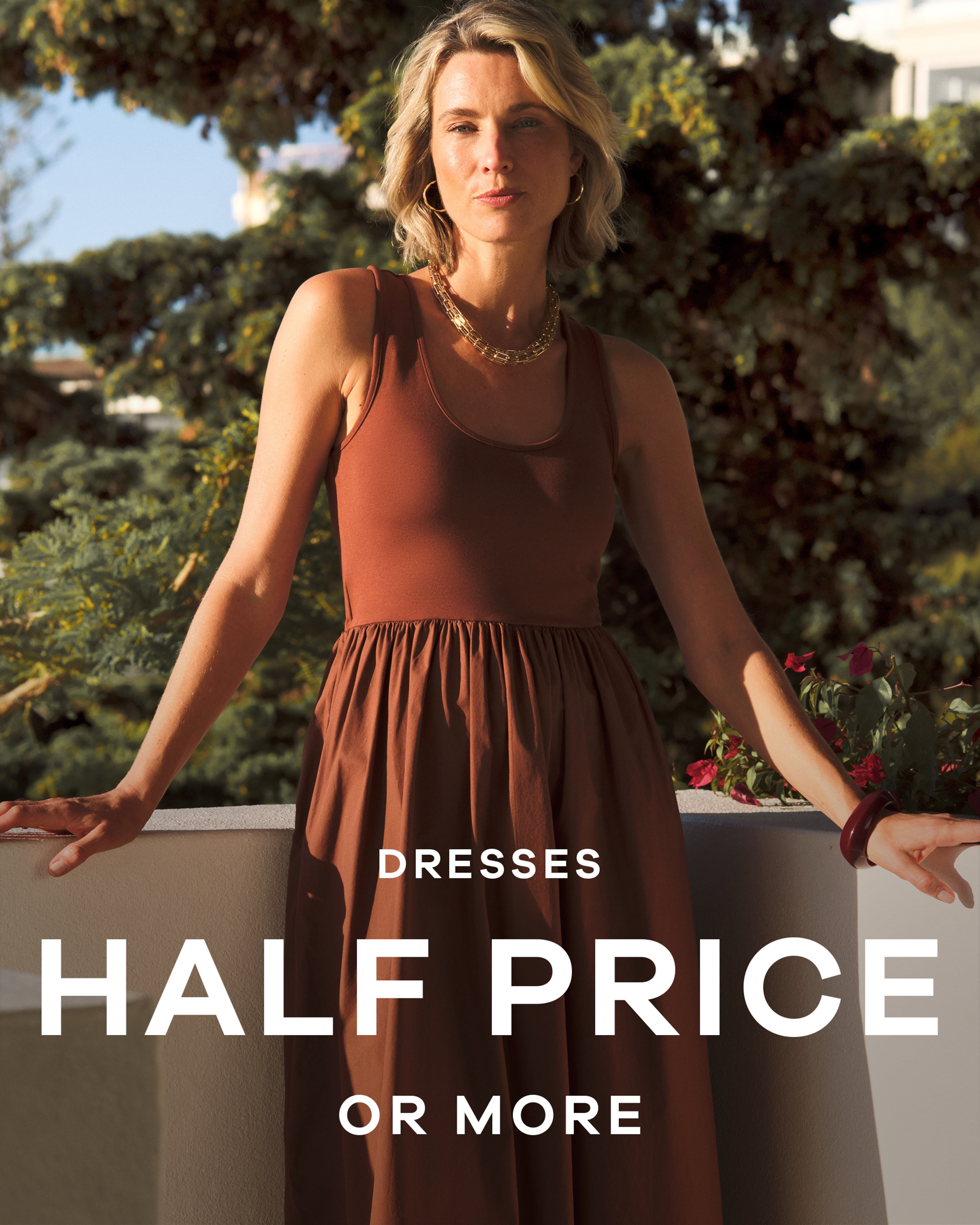 A lady wearing a brown dress leaning against a balcony