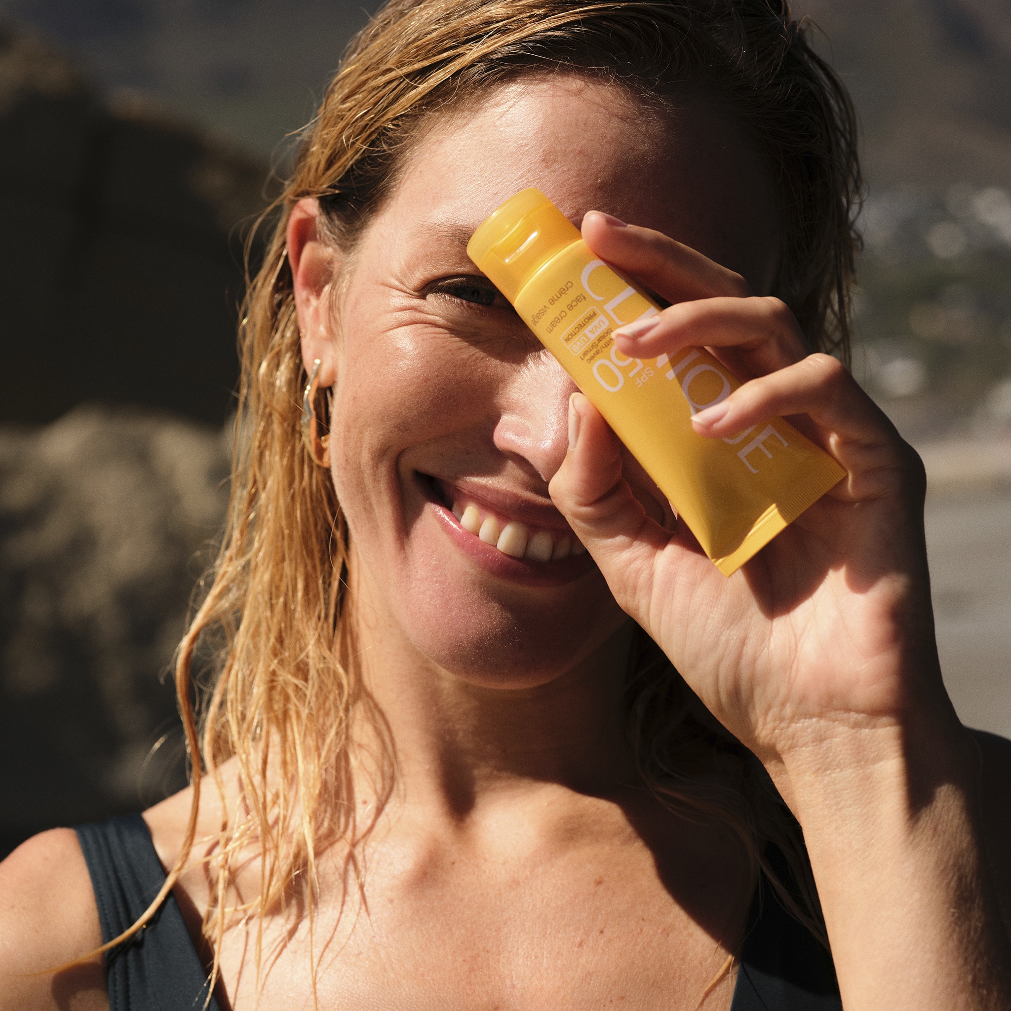 A lady holding a beauty product in front of her face.