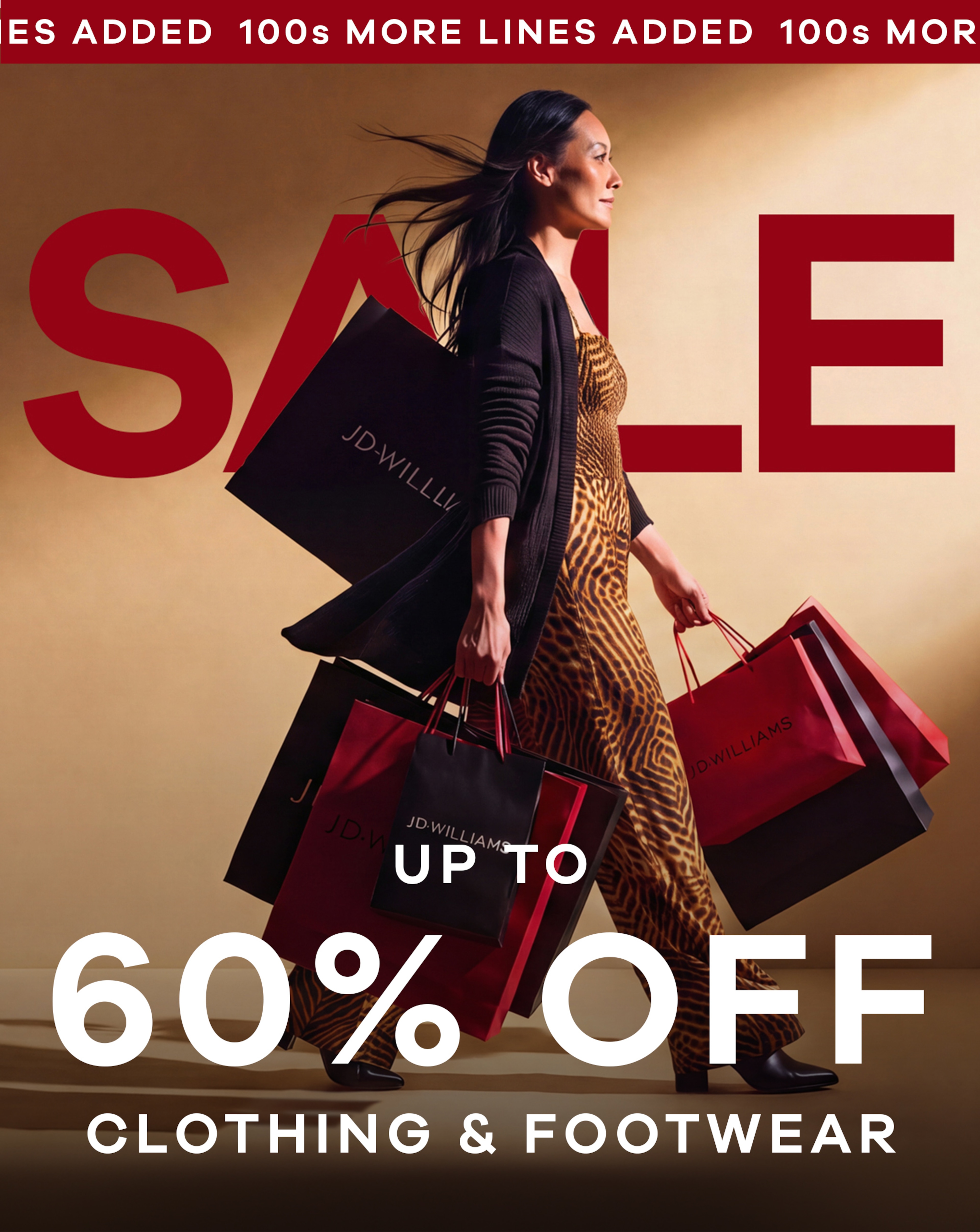 A woman walking from left to right with lots of JD Williams branded shopping bags. The word SALE in big red letters hehind her on the wall.
