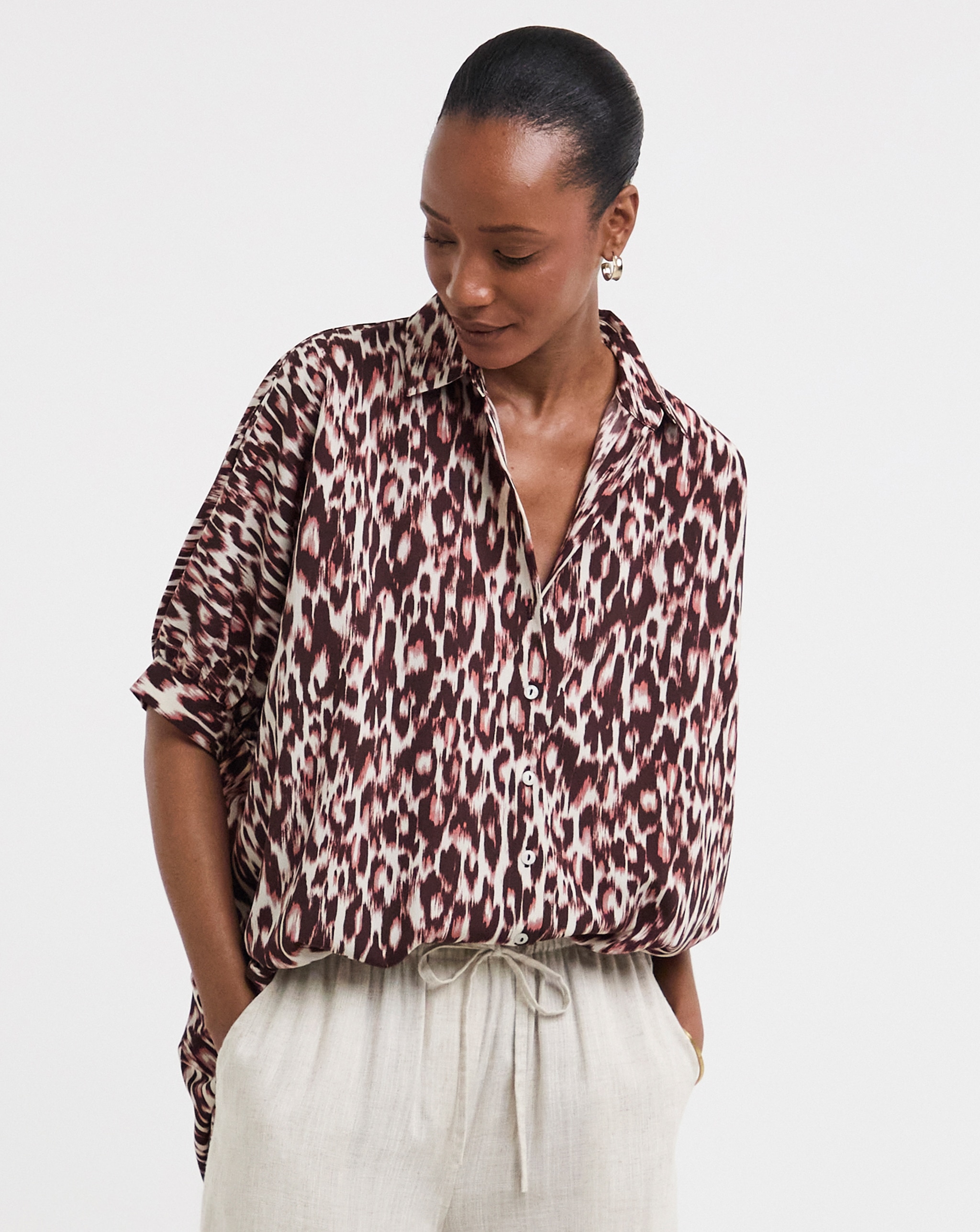 Person wearing a patterned long‑sleeve blouse with light wide‑leg trousers.