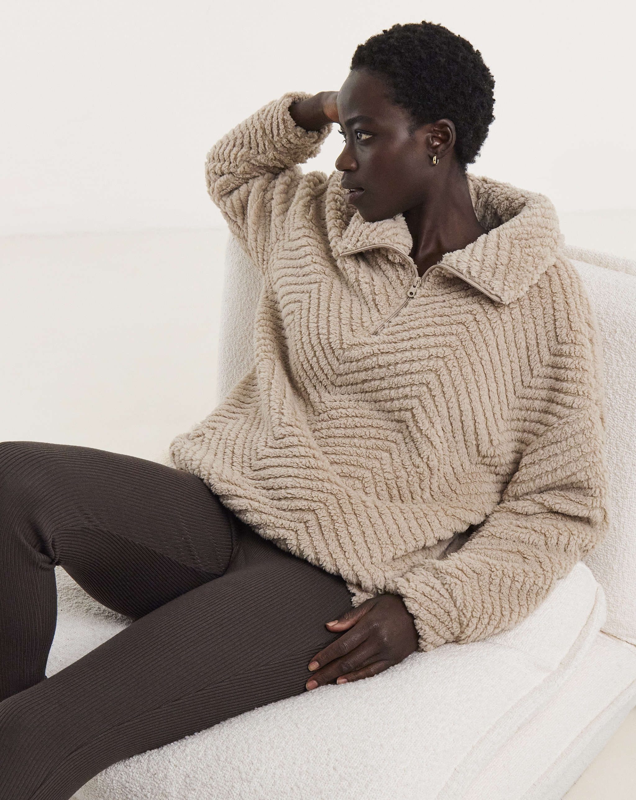 A woman sat down wearing beige and brown loungewear.