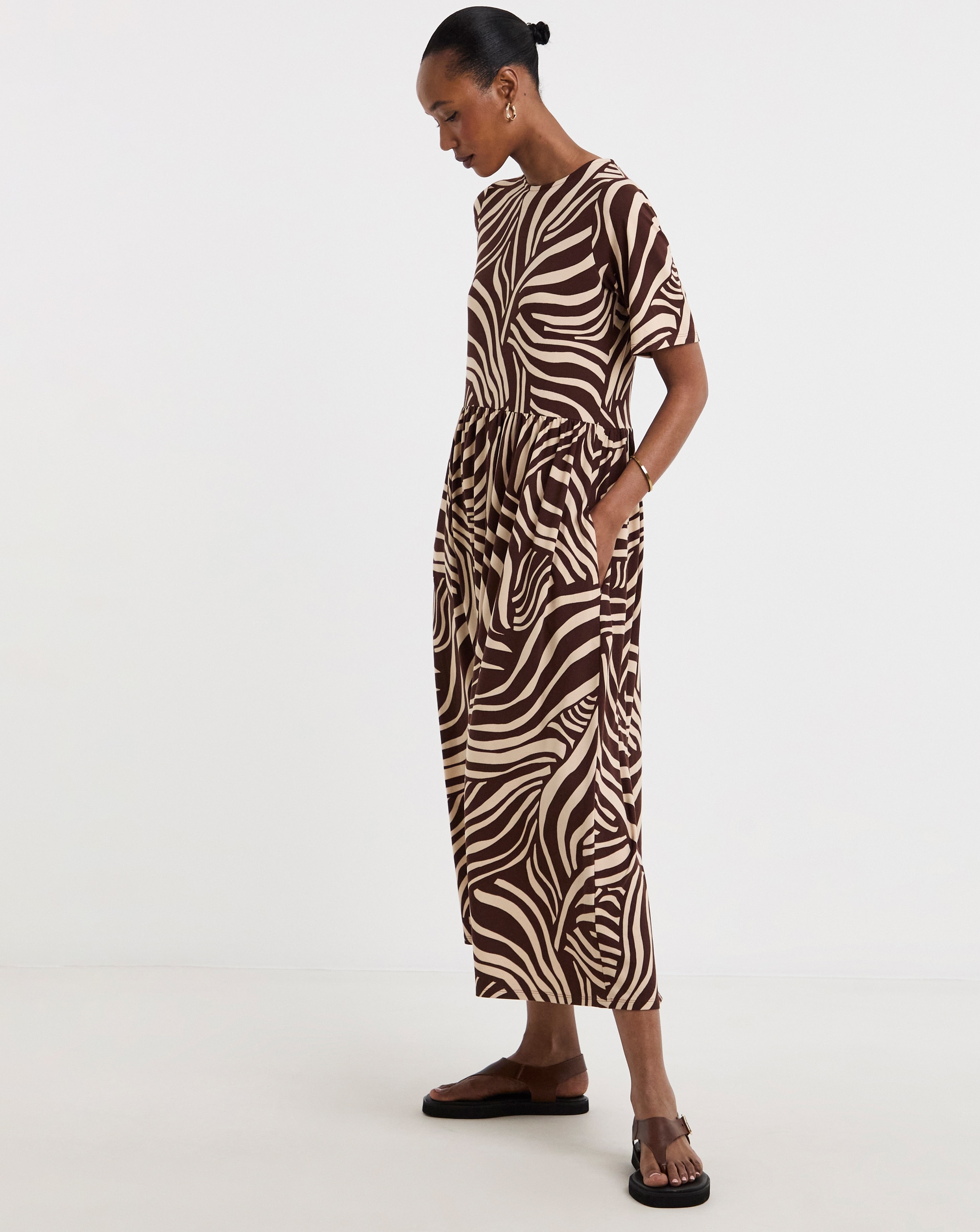 Person wearing a brown and cream abstract‑print short‑sleeve midi dress.