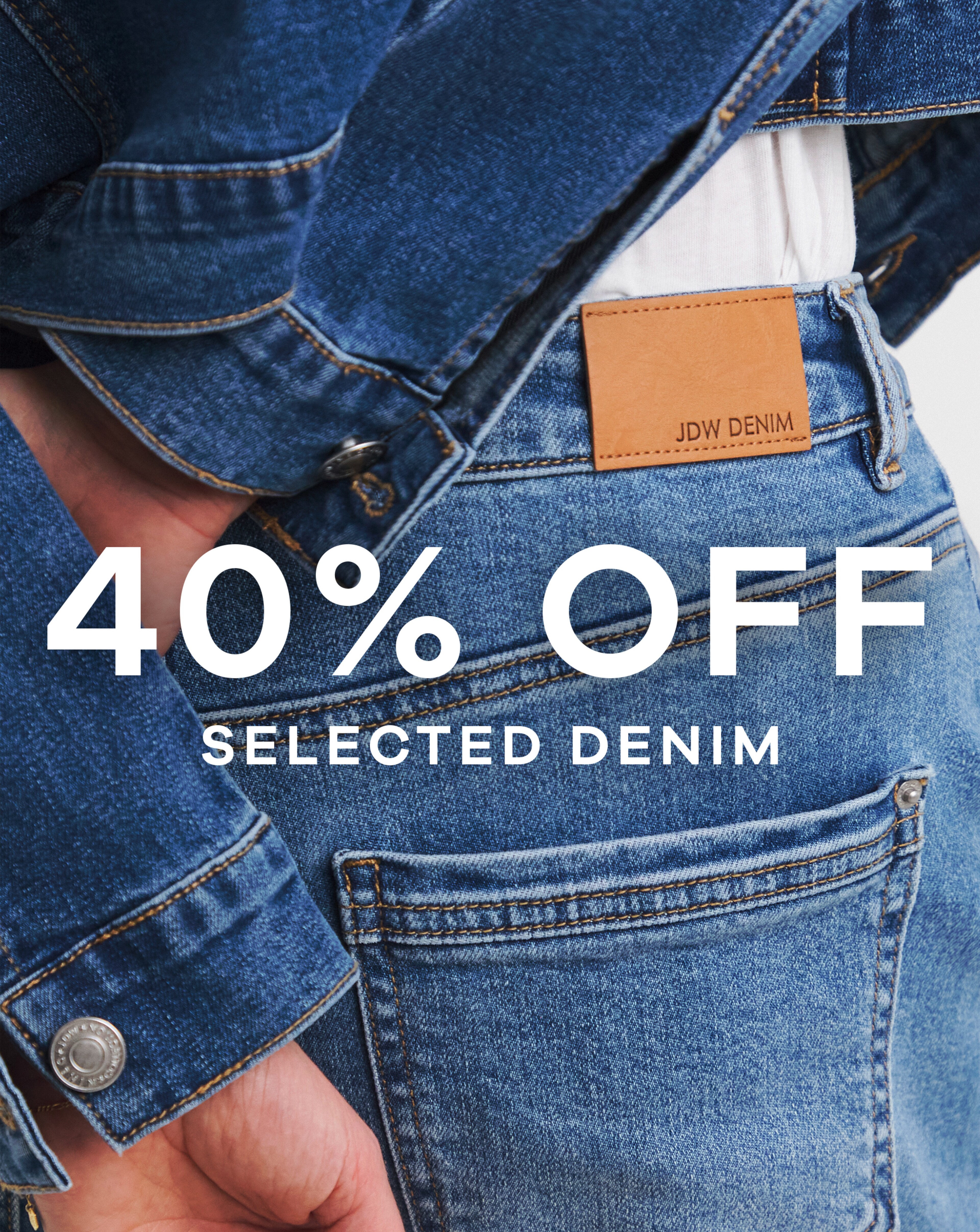 A close up image of a person wearing blue jeans and denim jacket