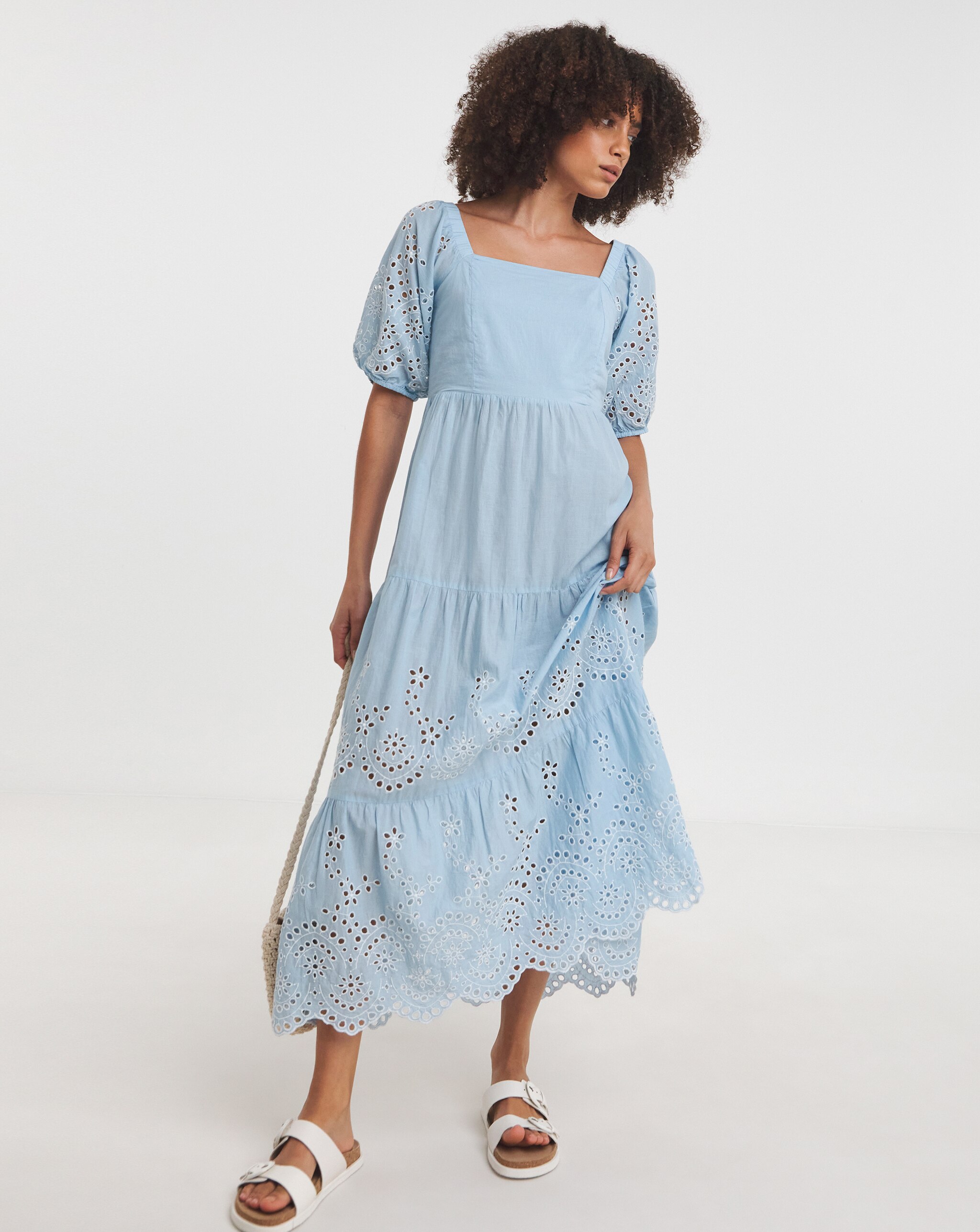 Person wearing a light blue broderie anglaise midi dress with puff sleeves and white sandals.
