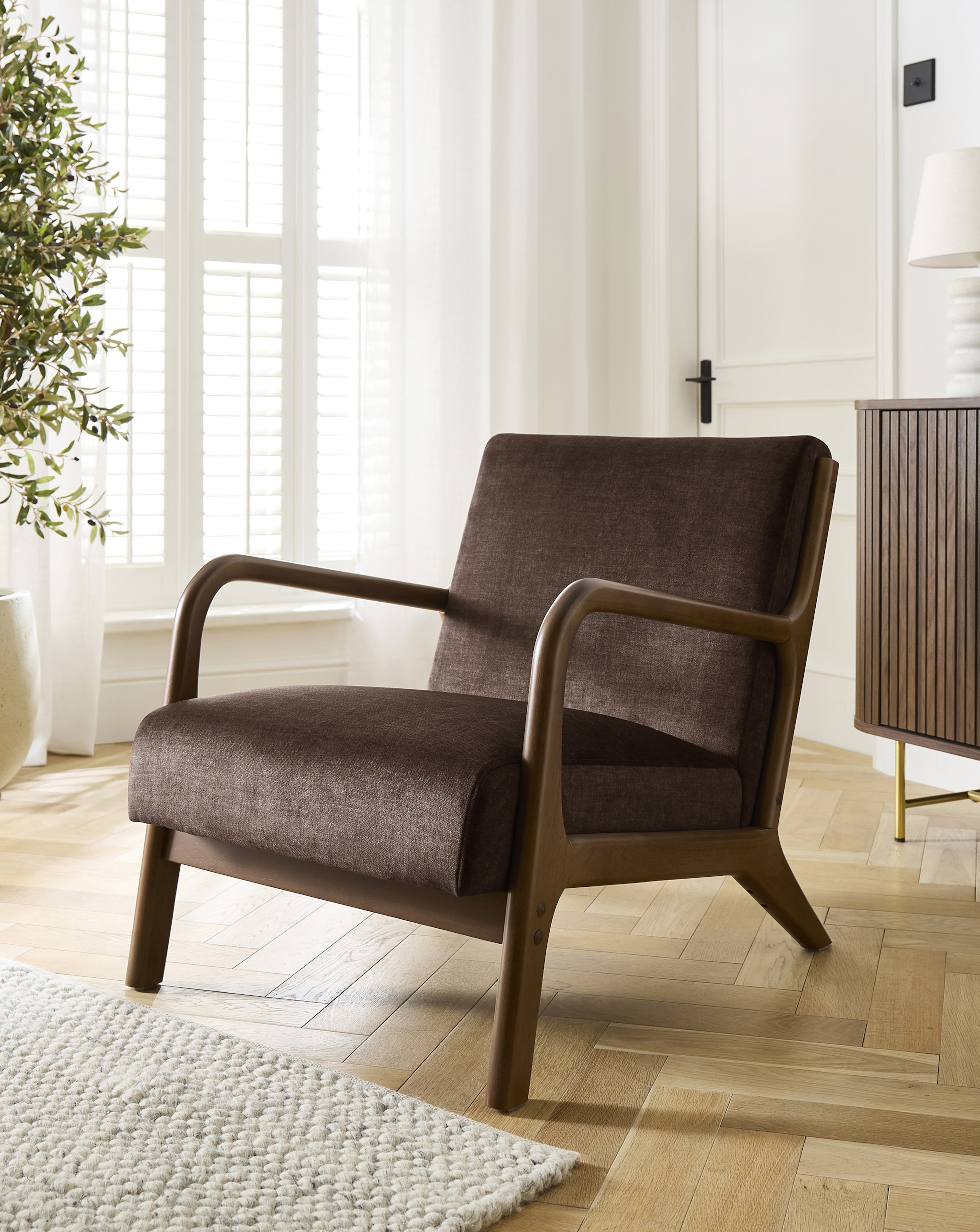 A brown arm chair with a wooden frame in a living room.