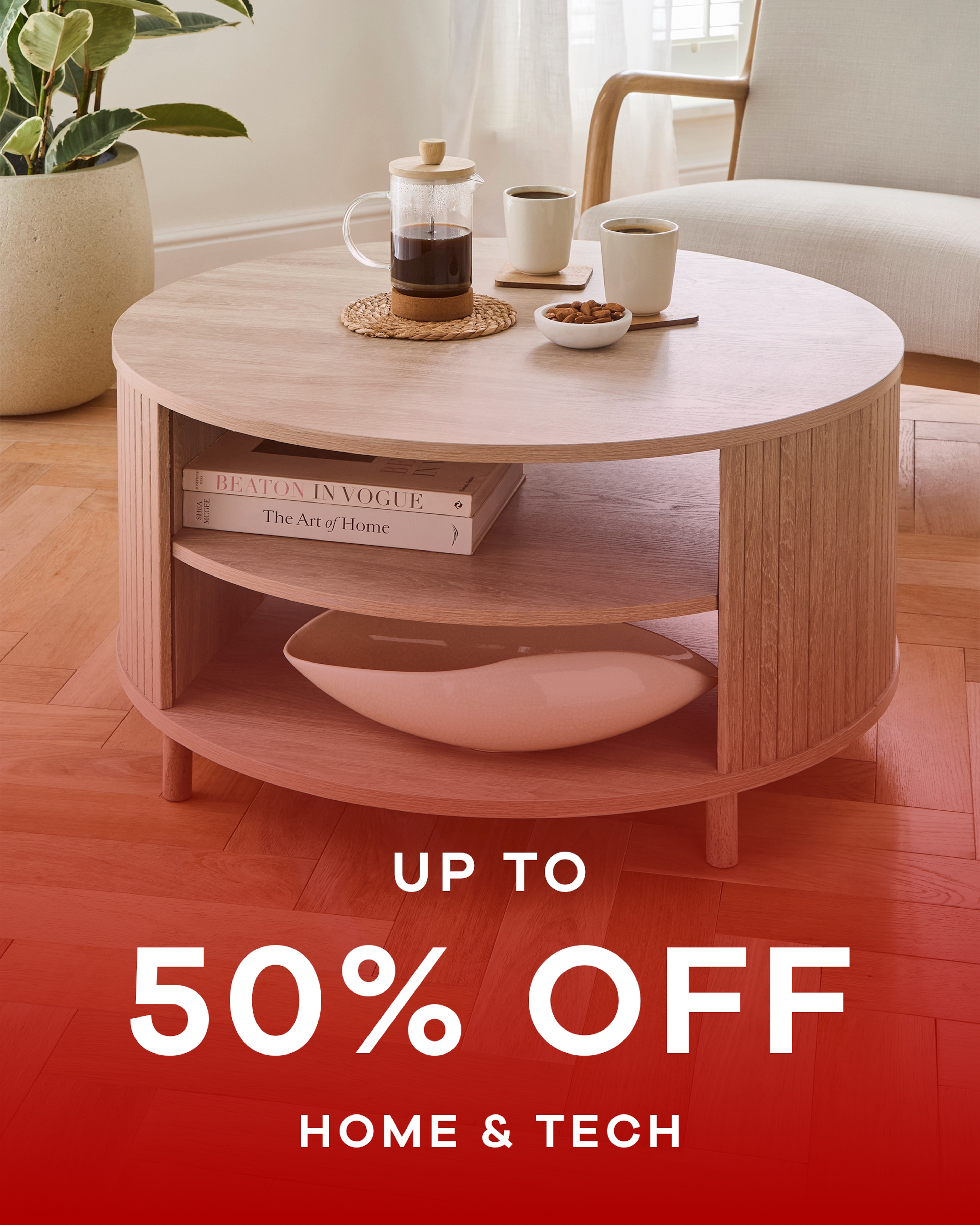 A round coffee table with a cafetière and two mugs in a room. Up to 50% off home & tech.