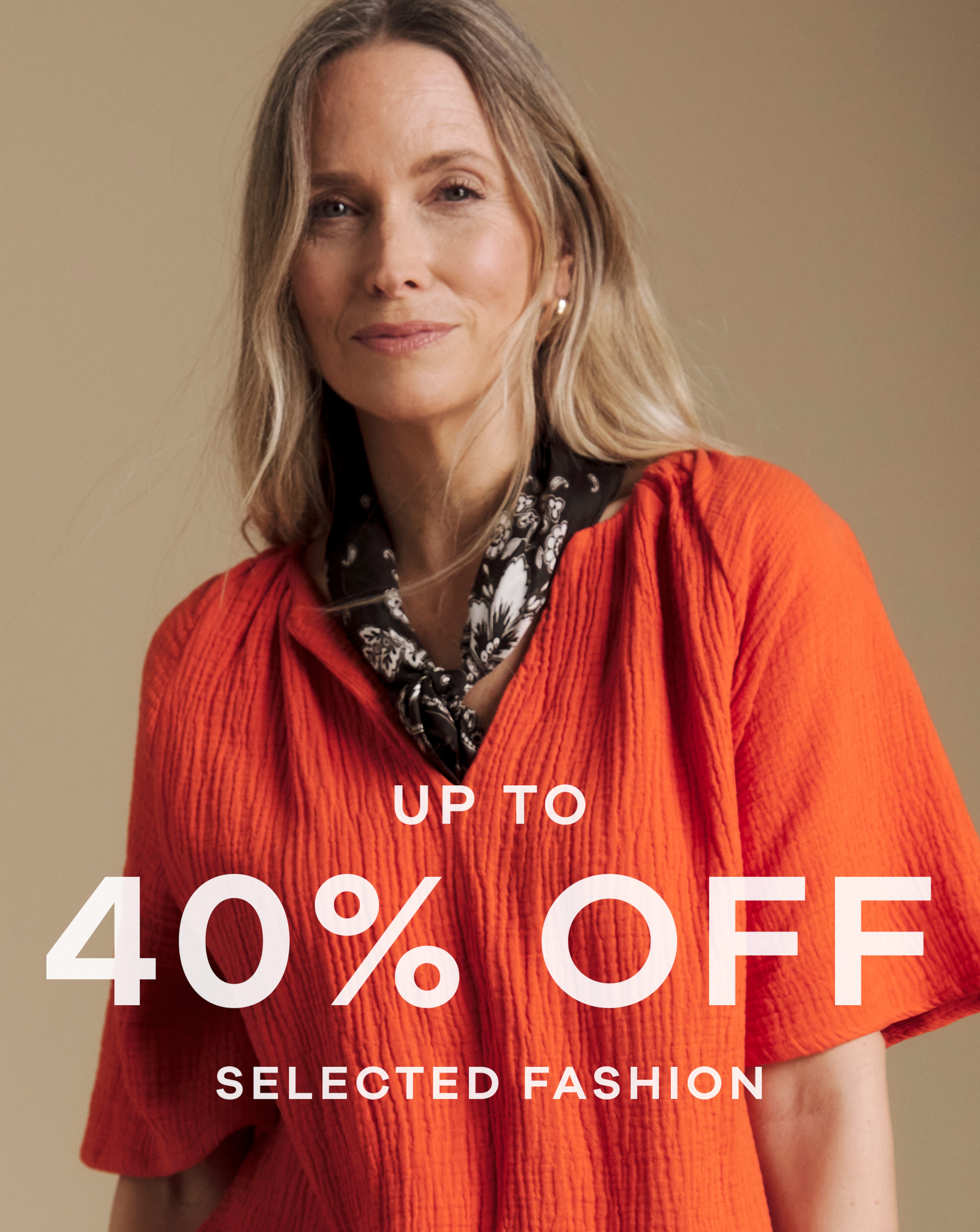A woman wearing an orange top and a black and white neck scarf.