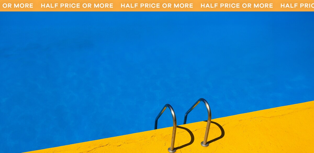 A swimming pool with yellow floor and some hand rails leading into the pool. Half price or more.