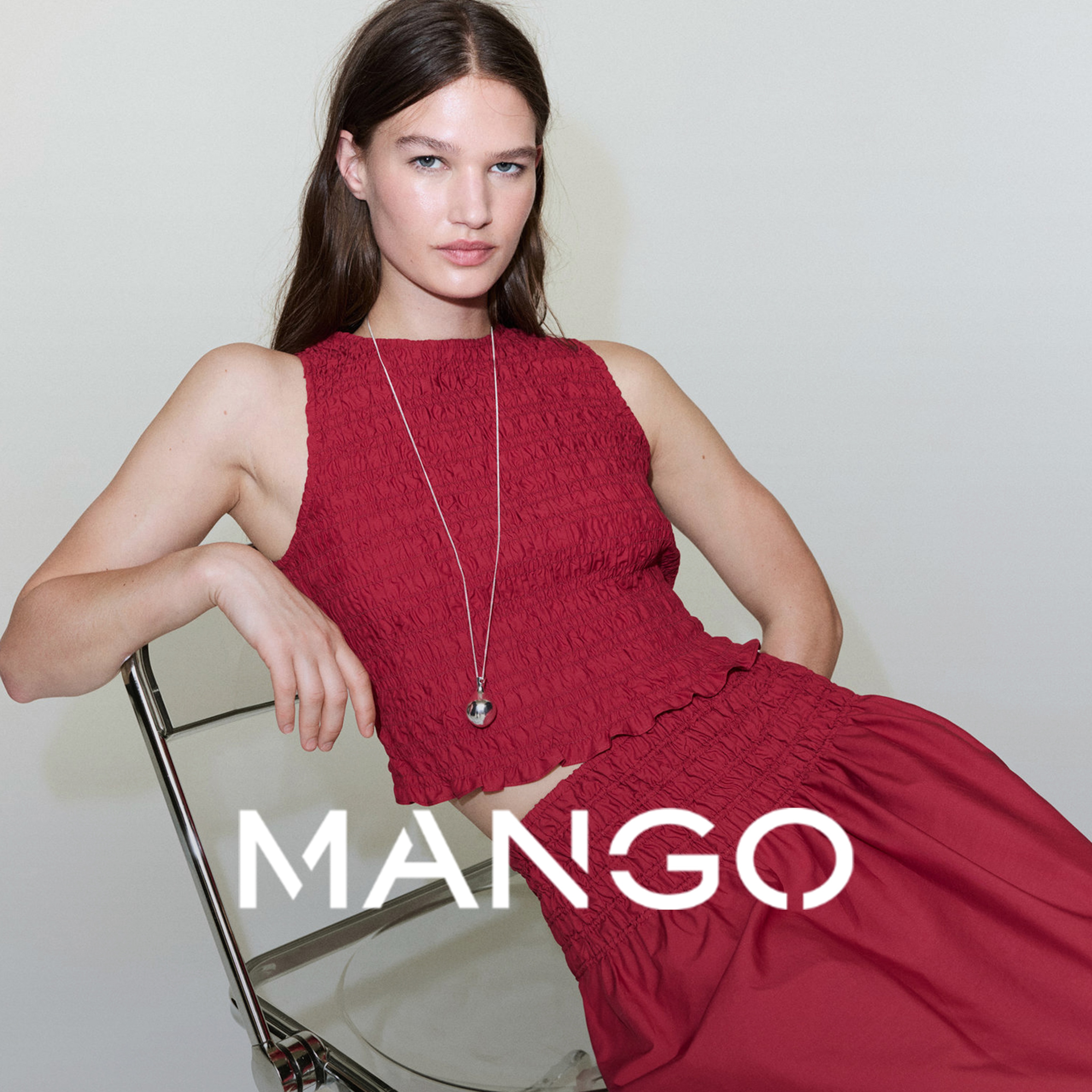 A woman wearing a red Mango dress sat in a chair