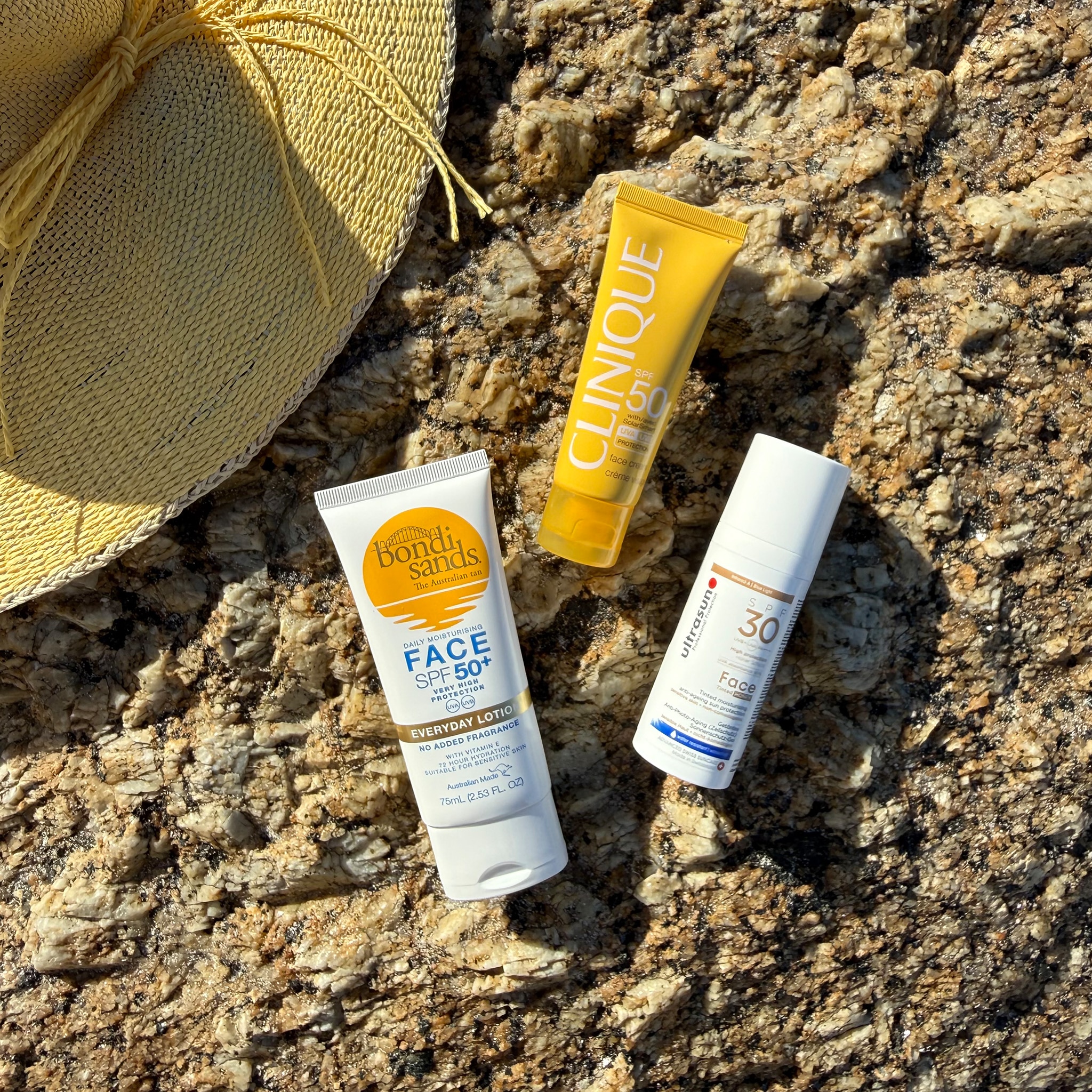 A range of beauty product laid out on a rock.