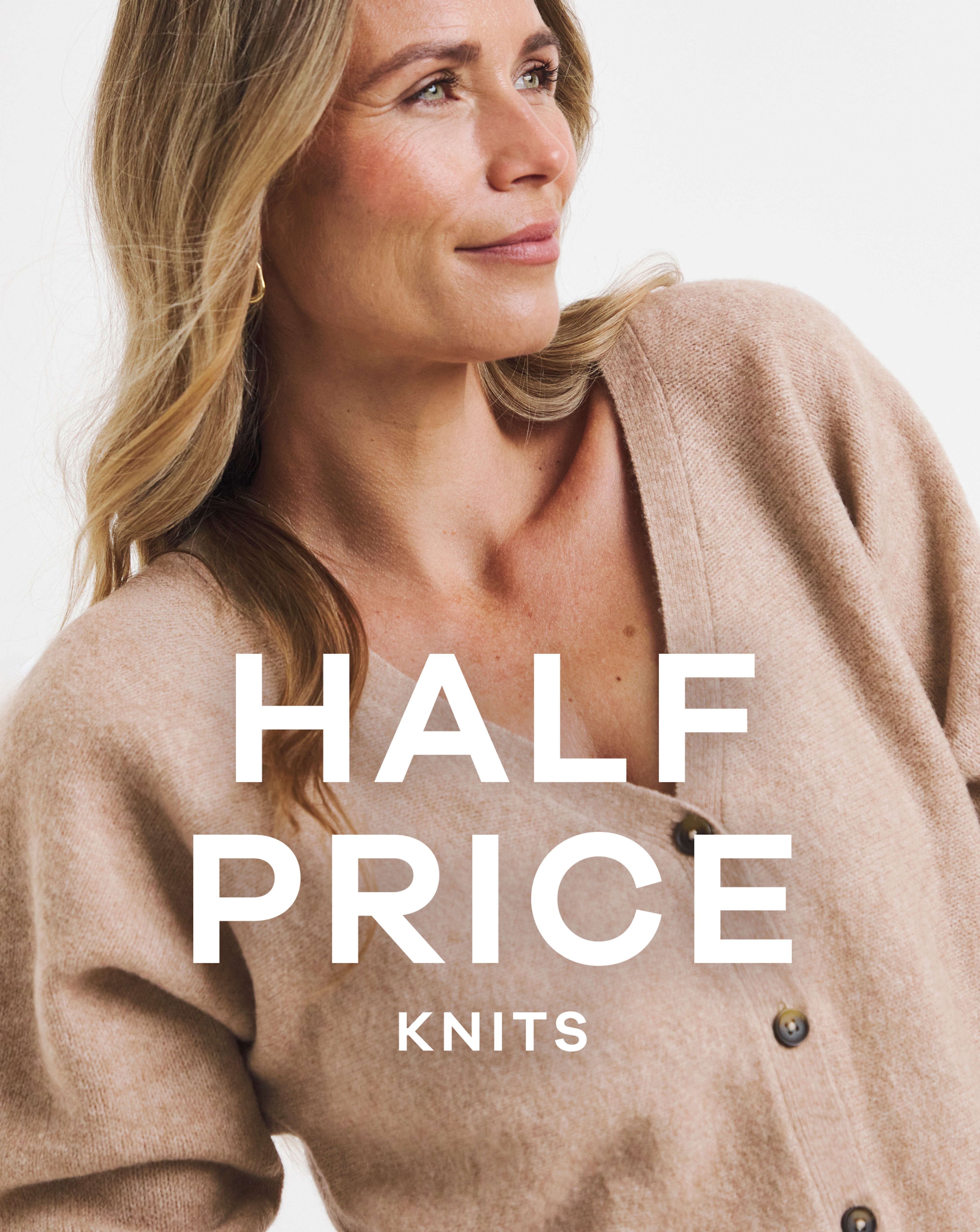 A woman looking to the right with a beige button up cardigan on.
