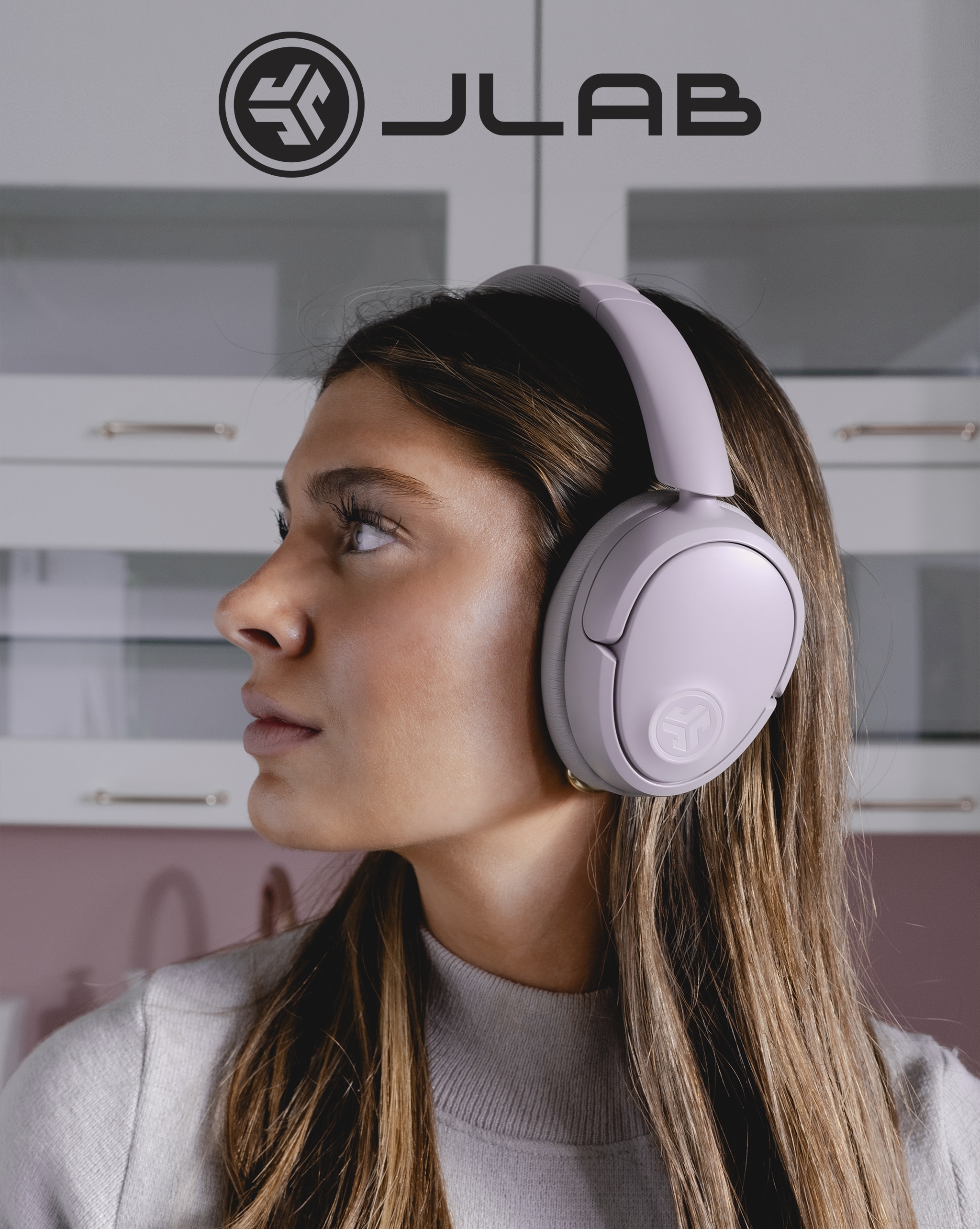 A person wearing a set of lilac JLAB headphones.