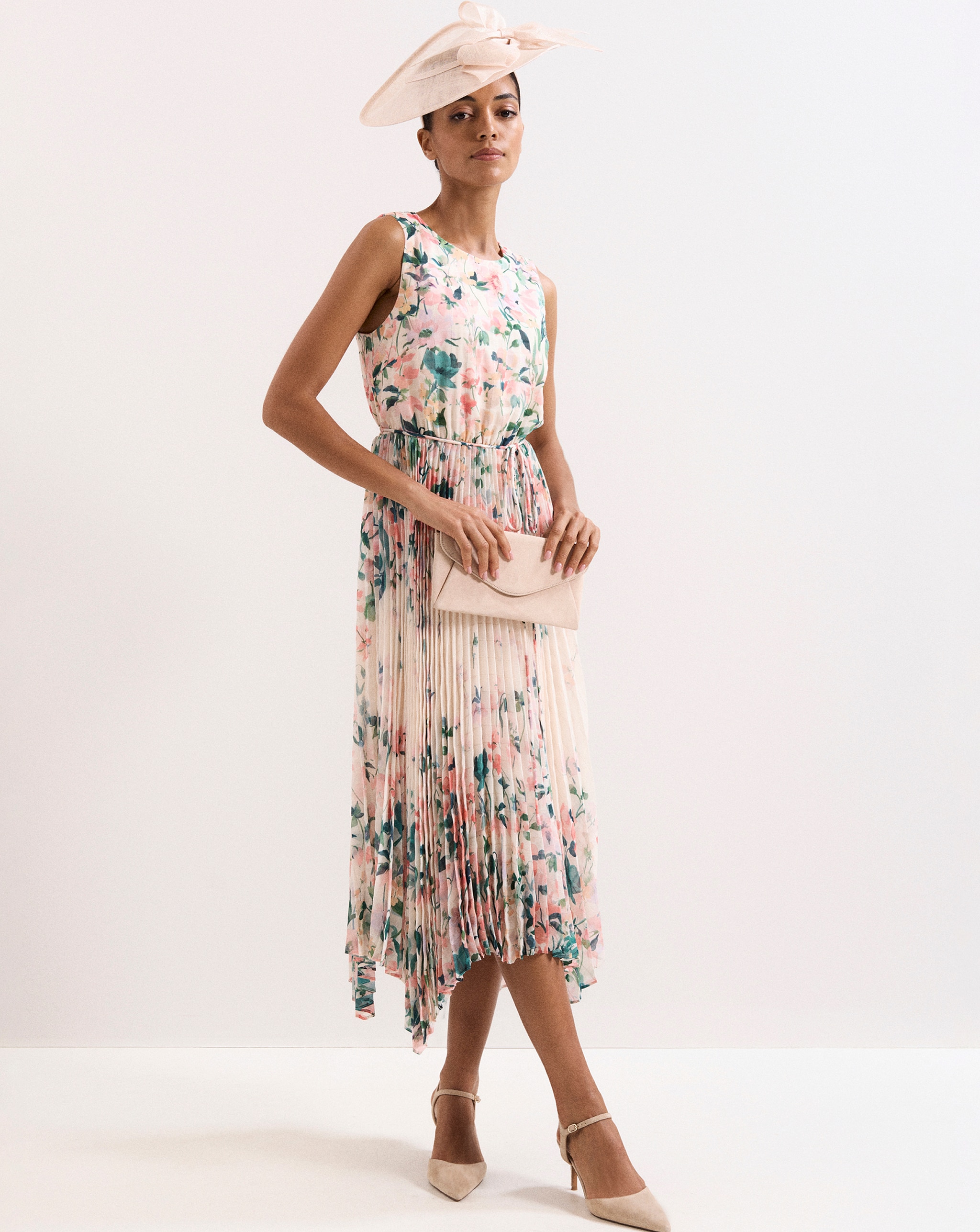 A woman wearing a pink and cream pleated floral dress.