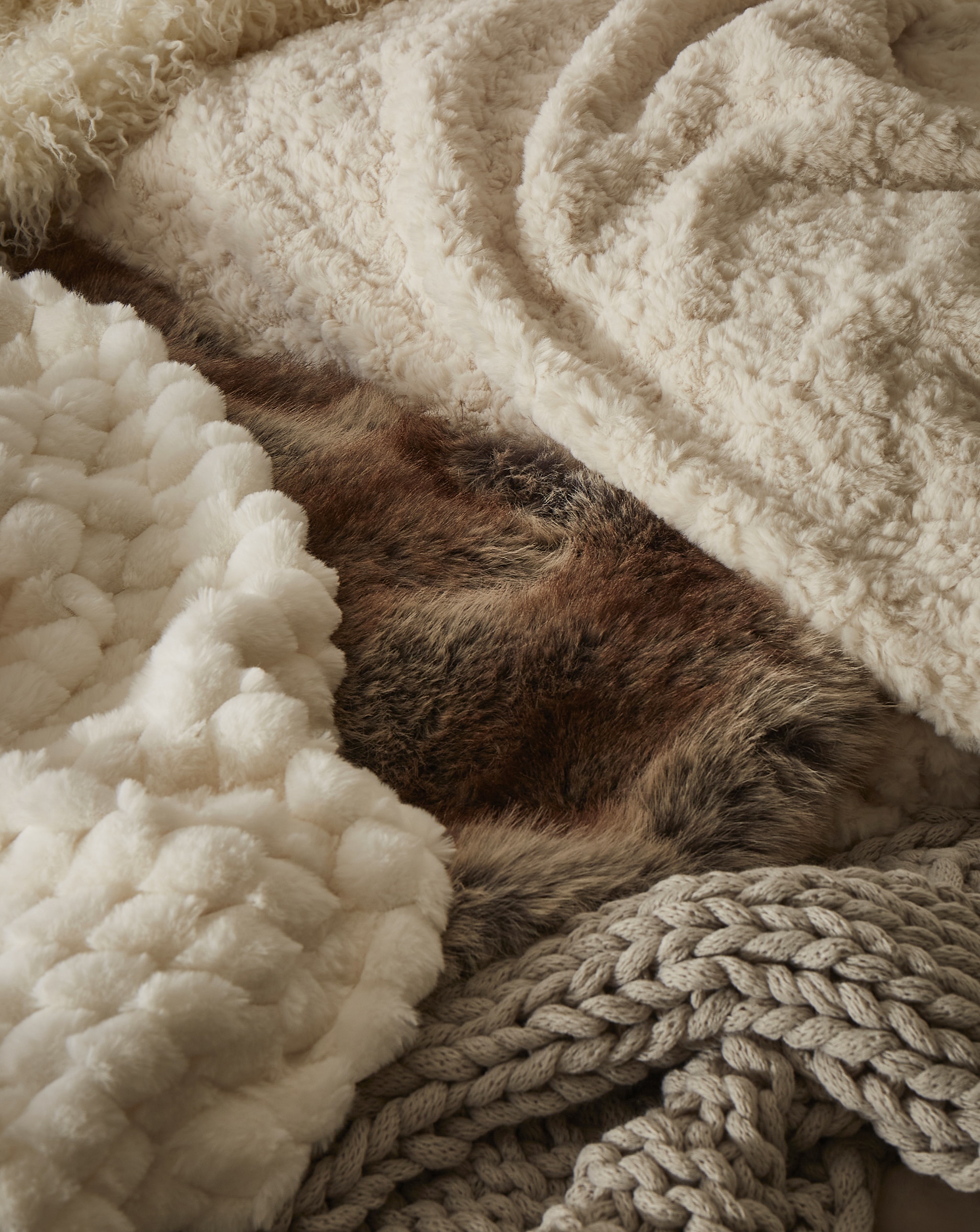 A few different throws and blankets overlaid on top of each other.