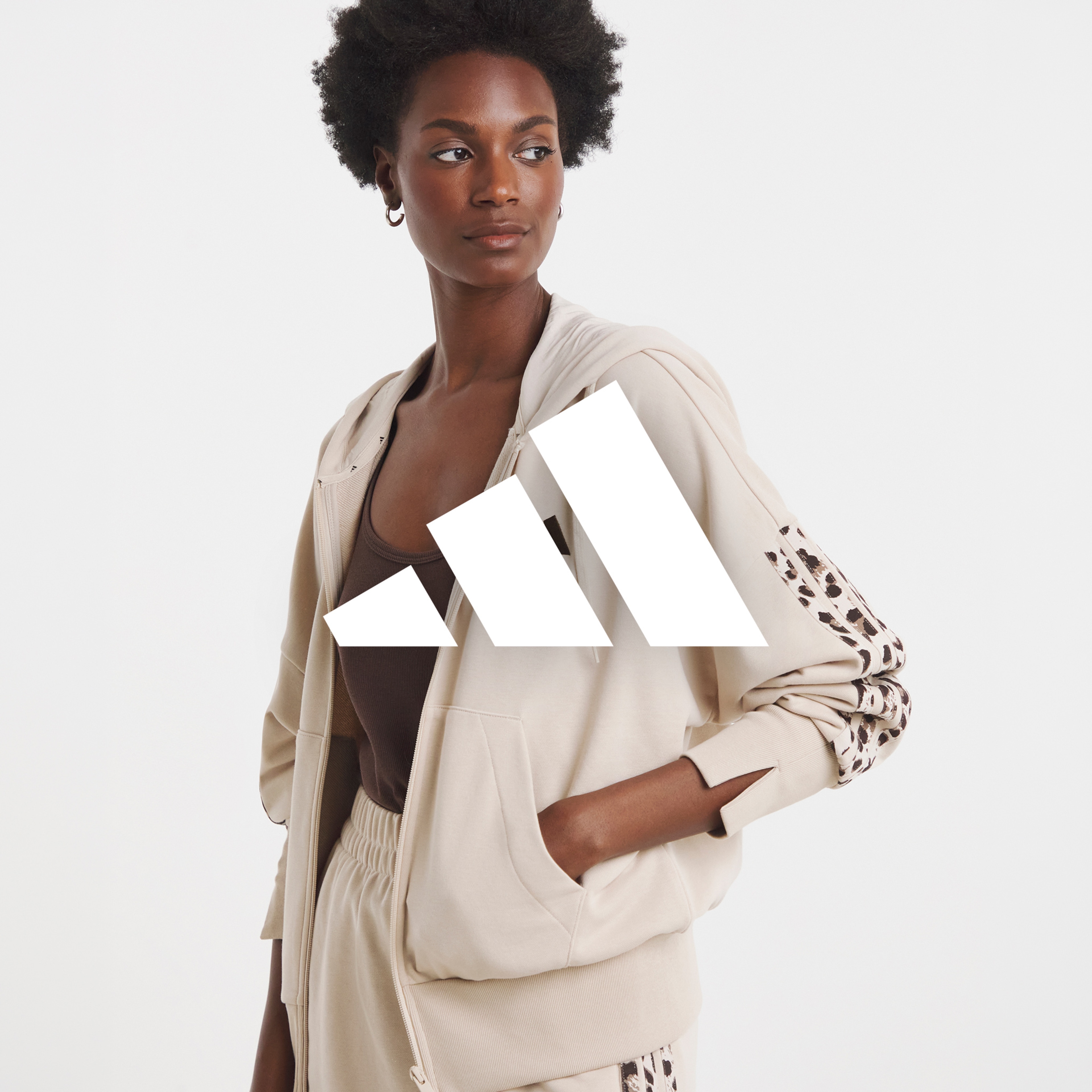 A woman wearing a light brown adidas tracksuit with animal print on it as part of the design.