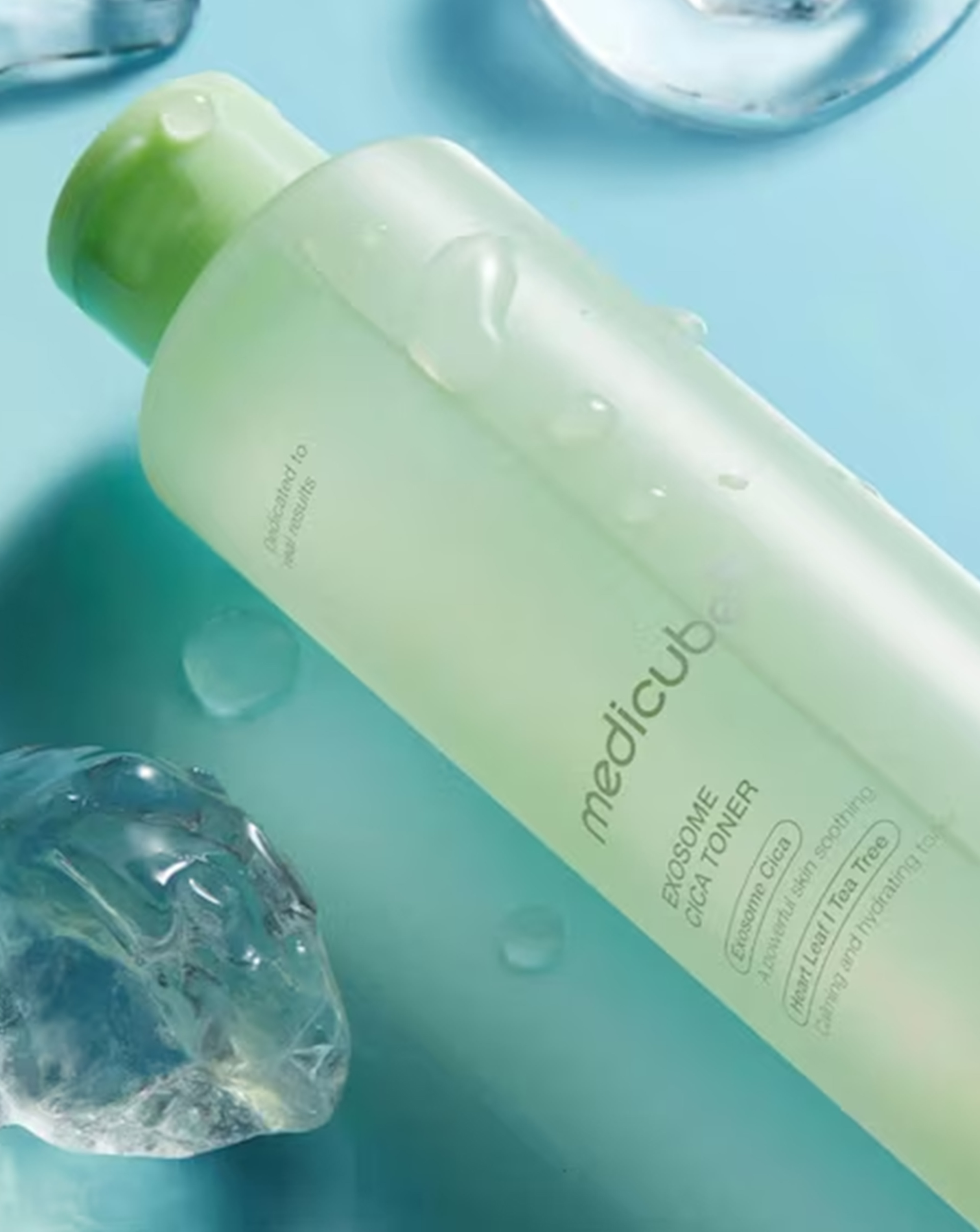 A bottle of Medicube exosome cica toner lay on its side on a blue surface.