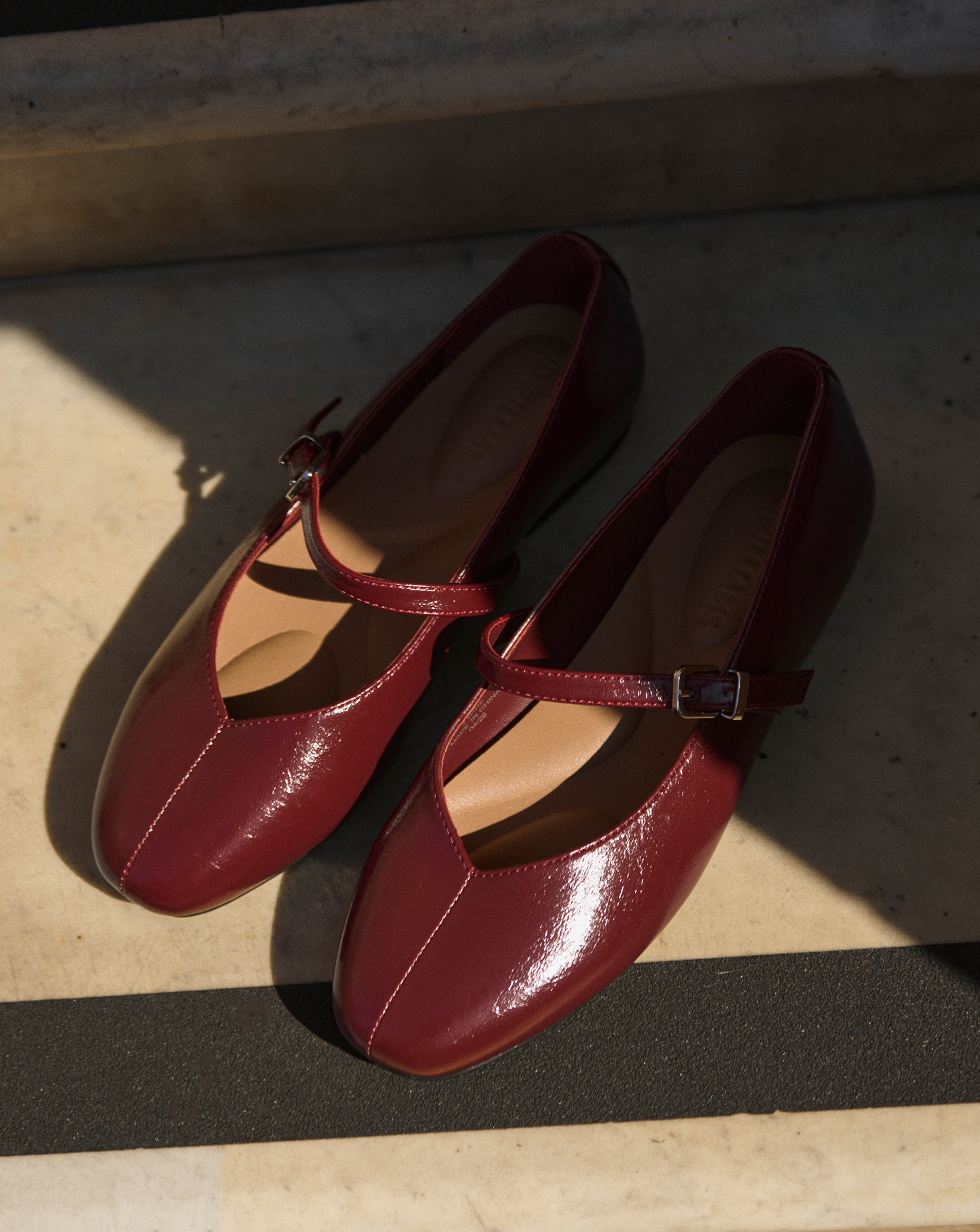 A pair of burgundy shoes on a step outside.