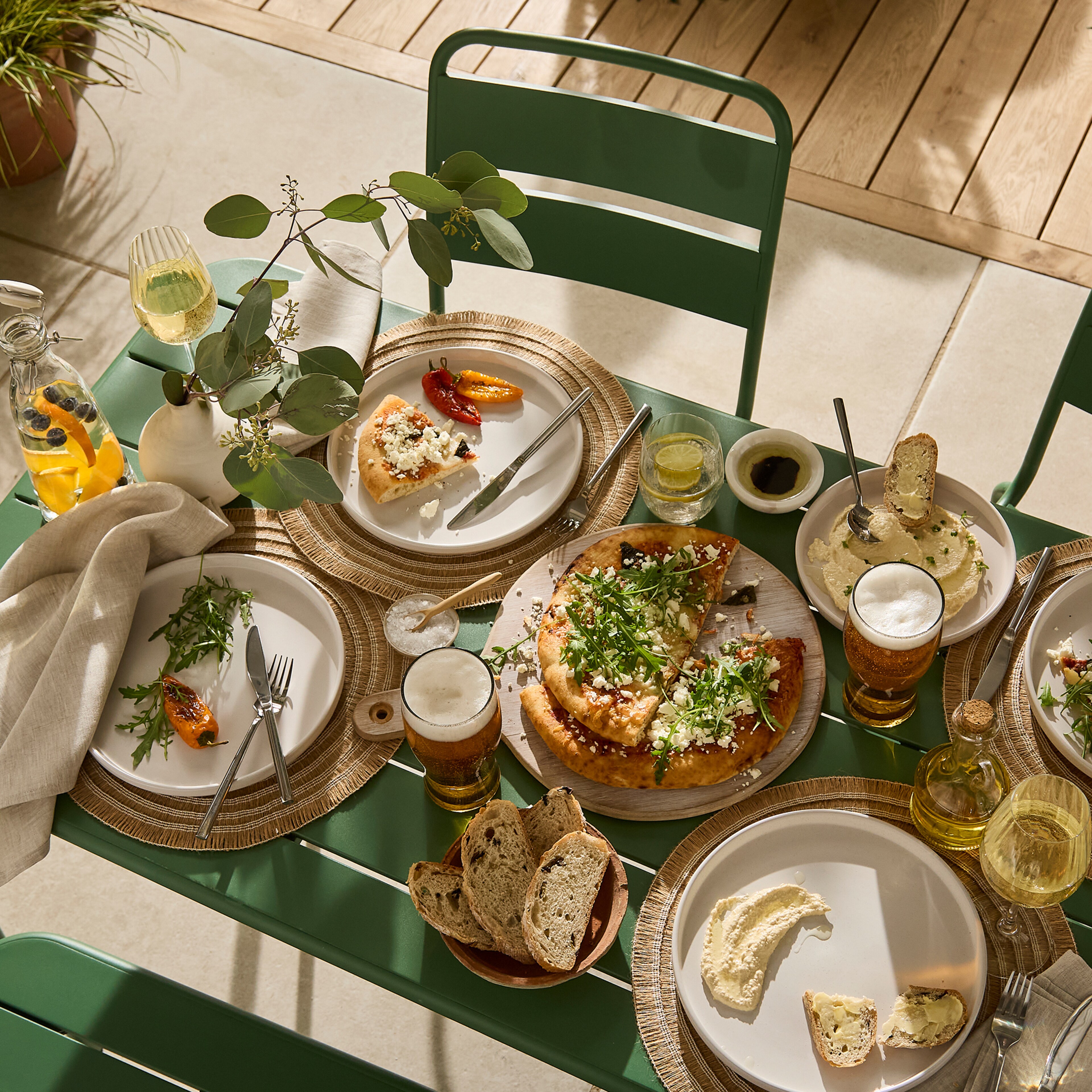 An outdoor dining table with food and drinks