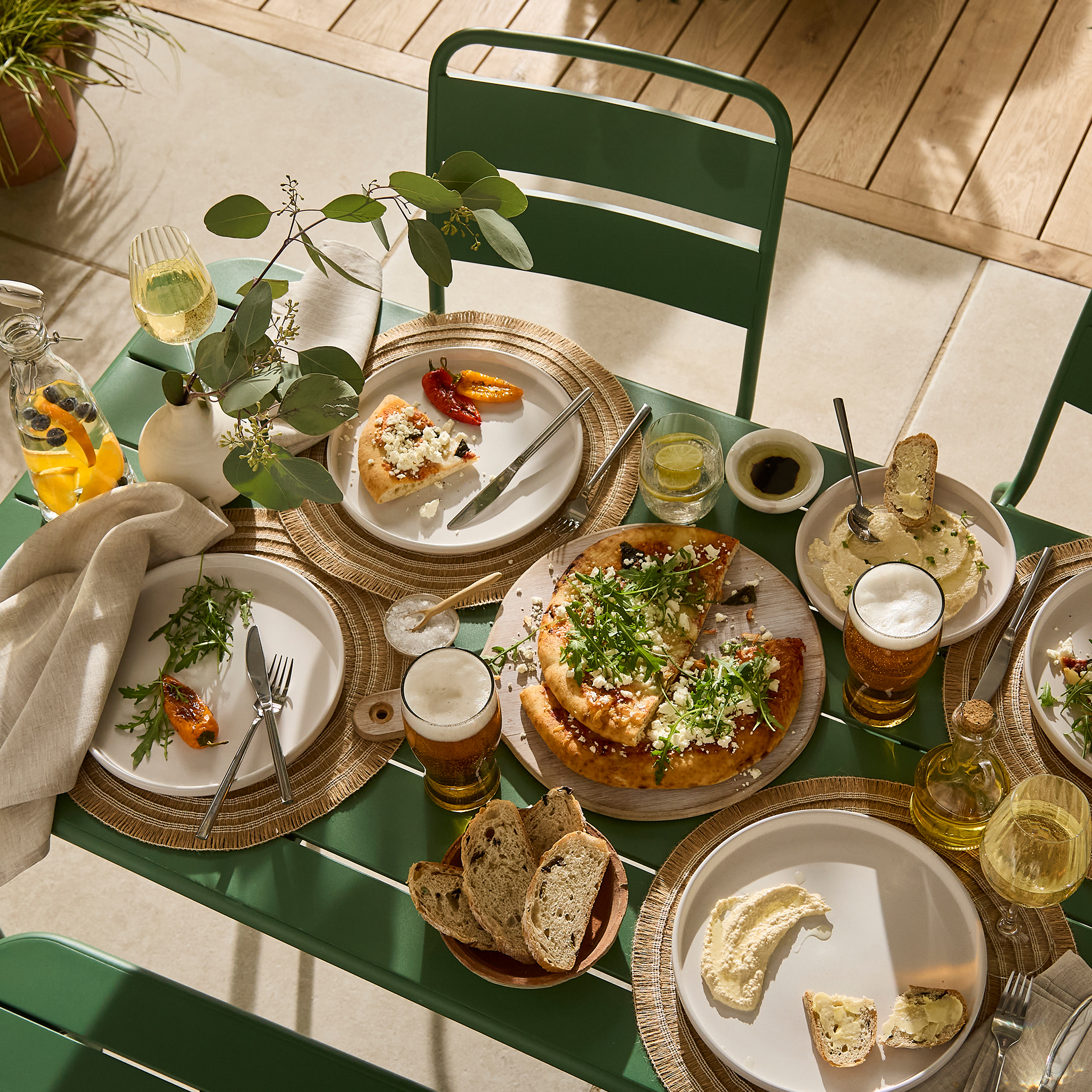An outdoor dining table with food and drinks
