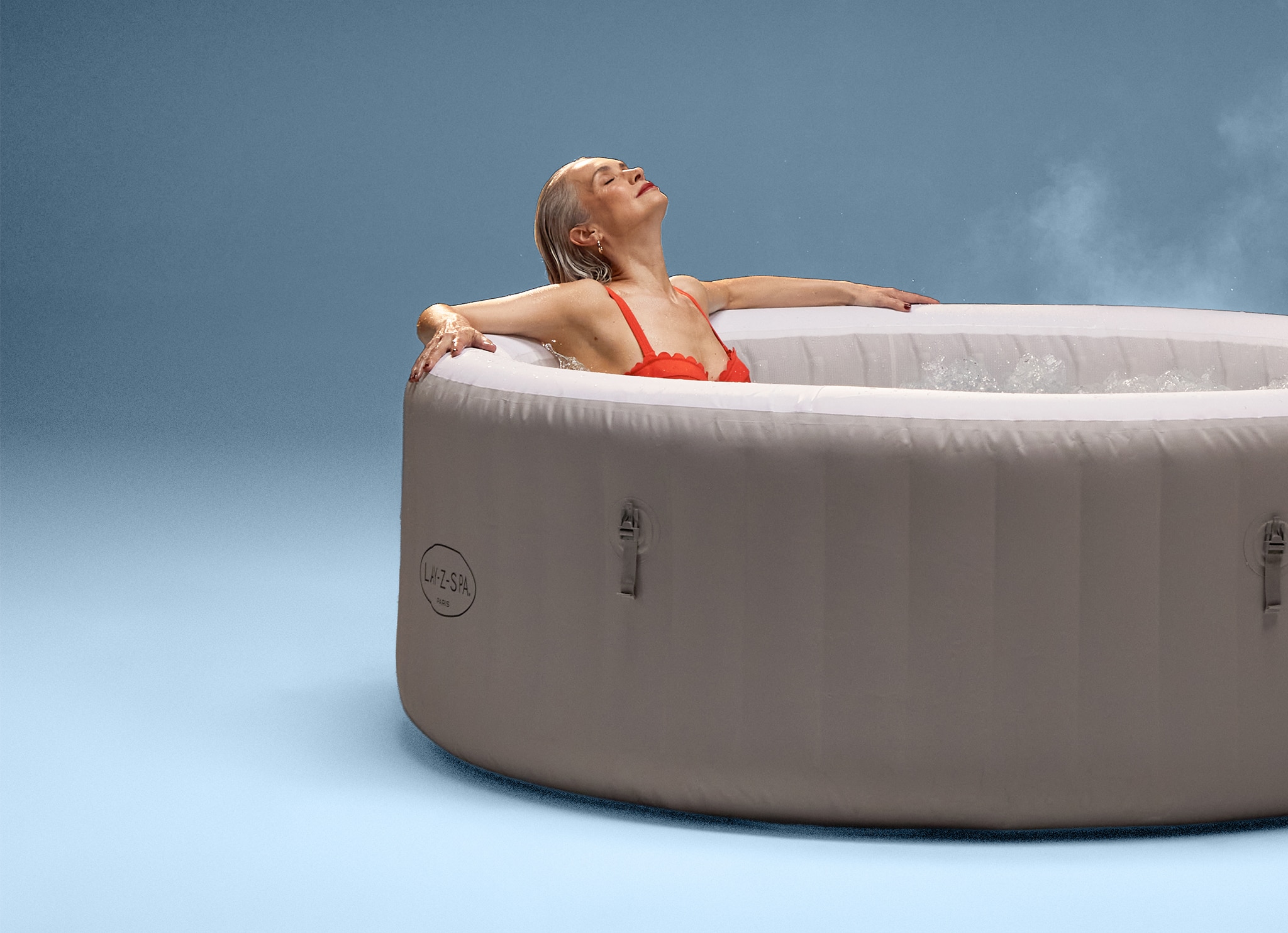 A woman wearing a red swimming costume in an inflatable hot tub.