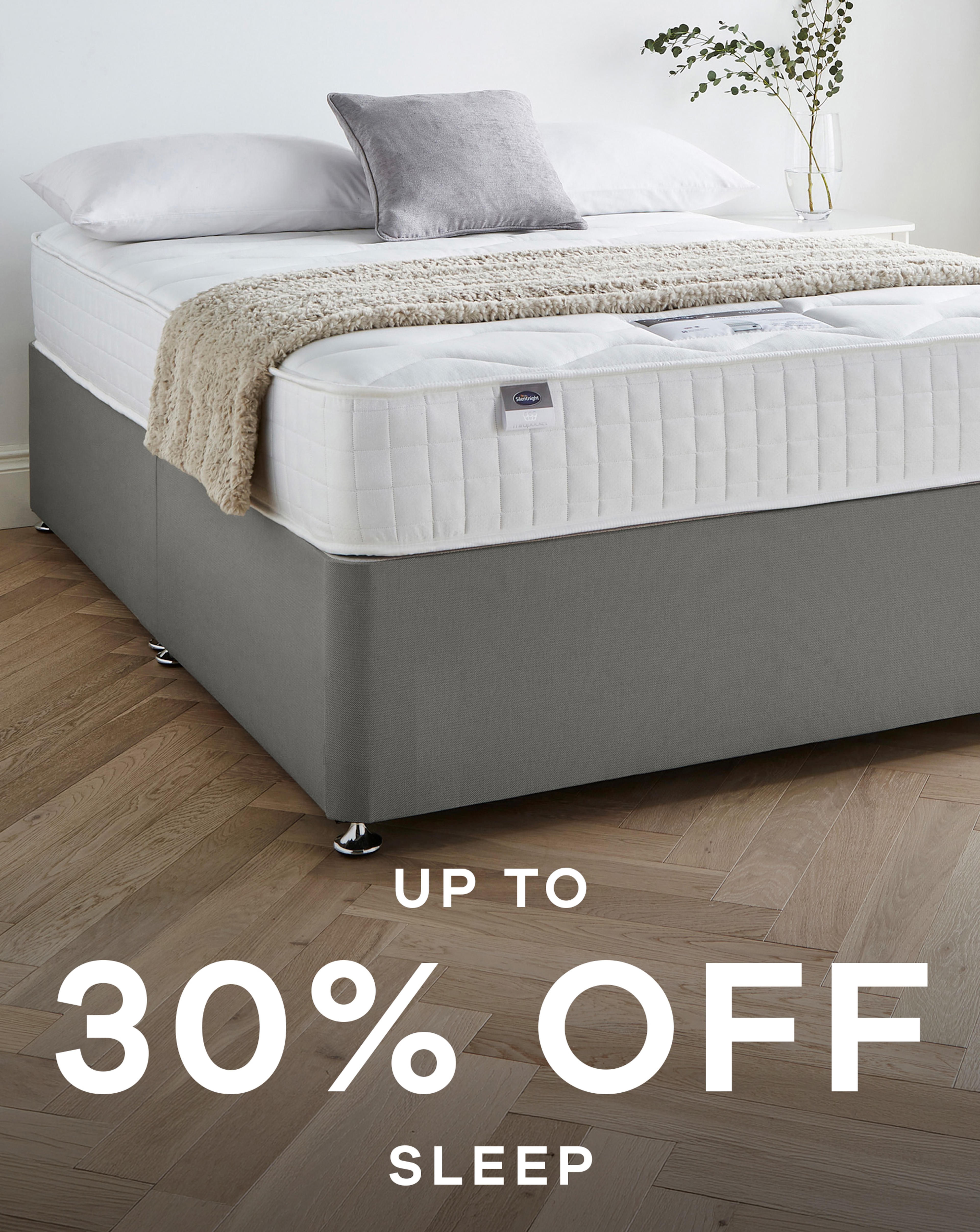 A bed with a bare mattress and pillows in a room with white walls and laminate wooden floor. Up to 30% off sleep