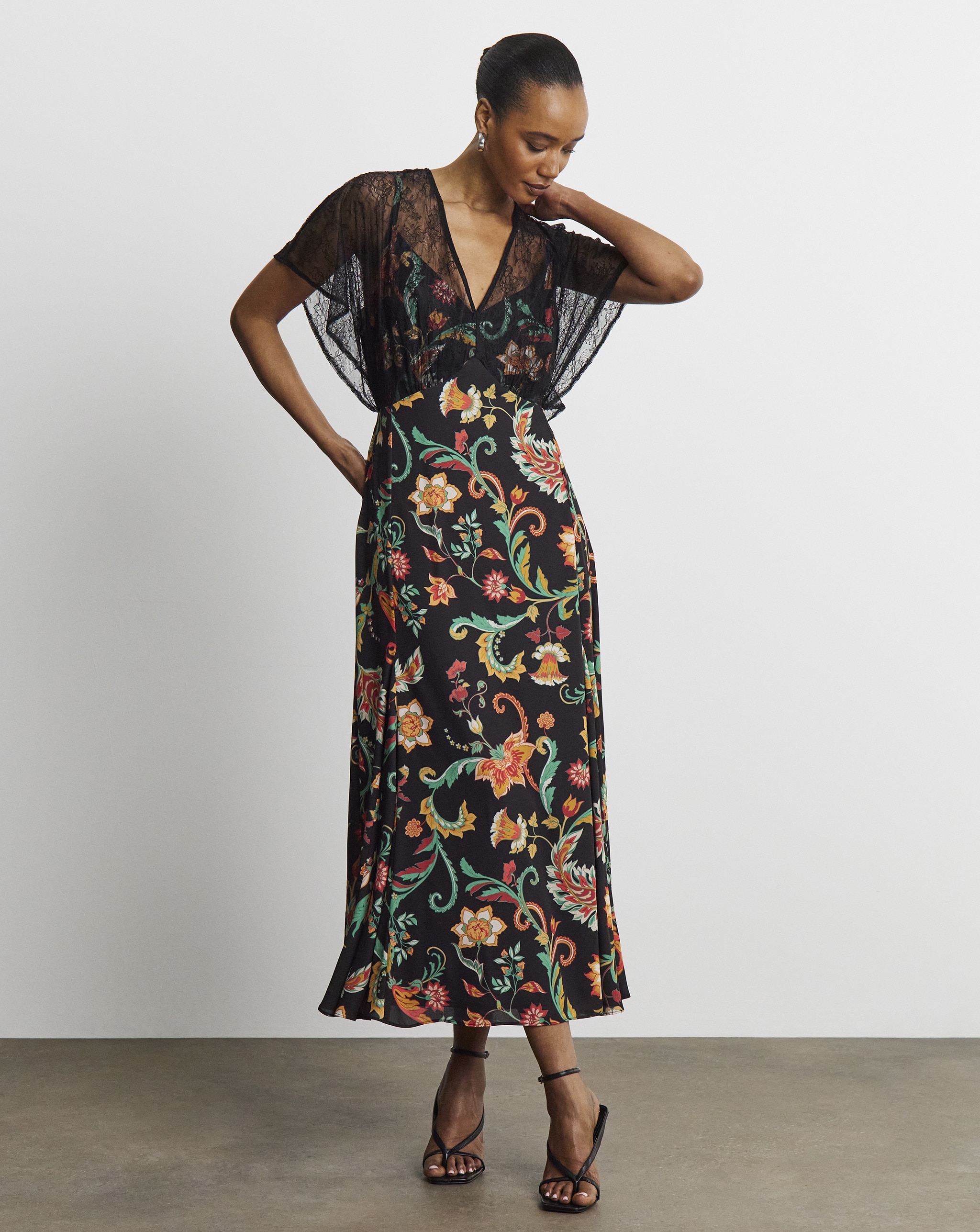 A lady wearing a black dress with colourful floral patterns on.