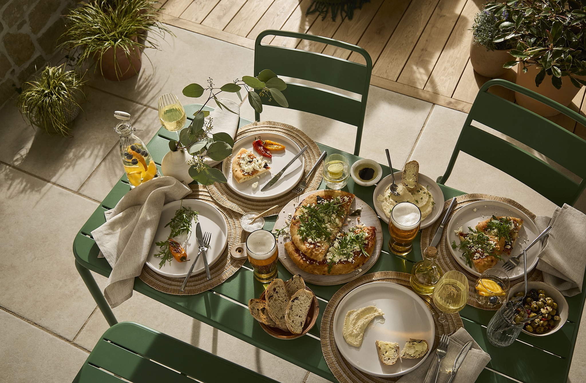 An outdoor meal in progress with green garden furniture.